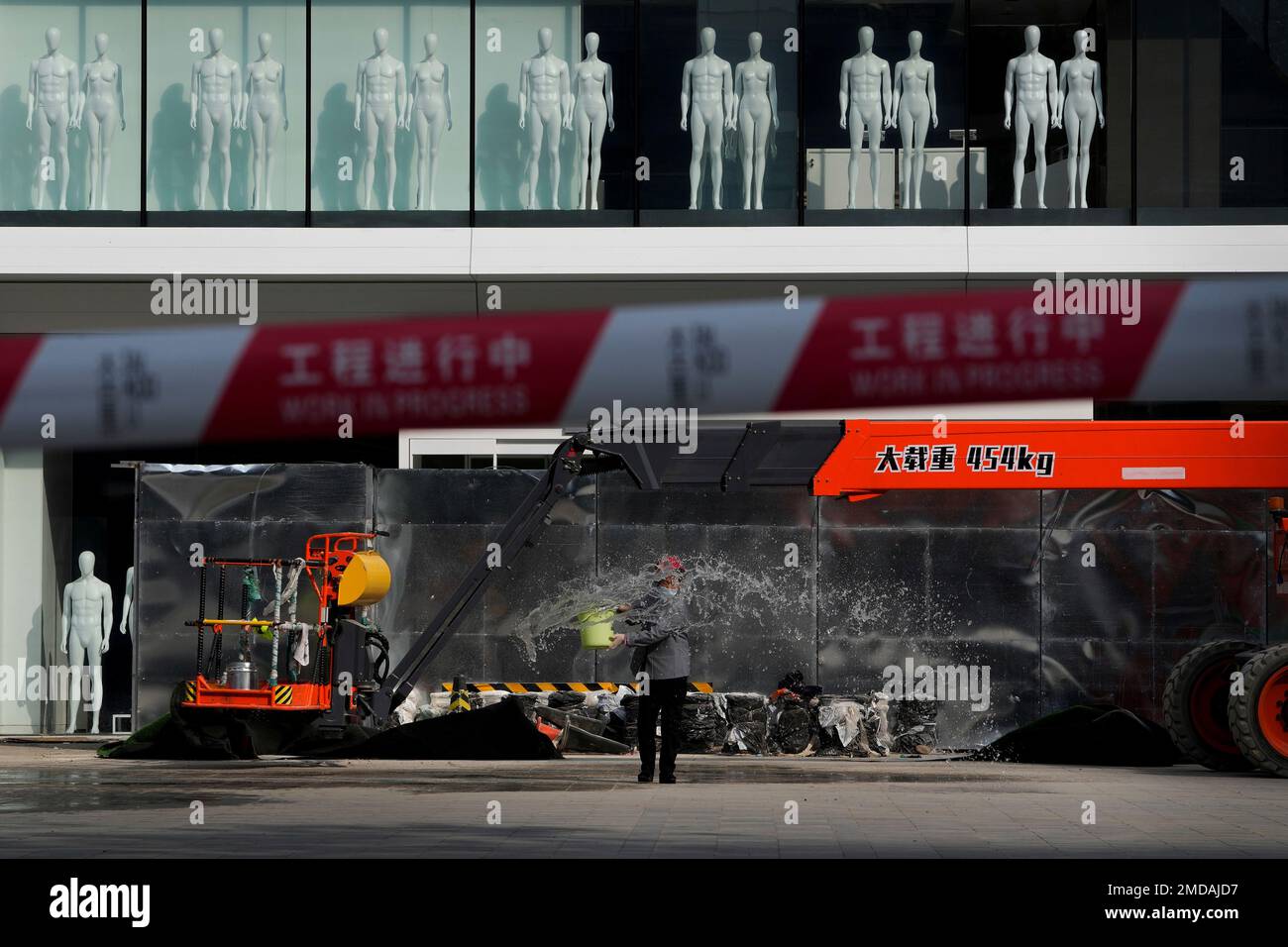 A worker sprays water near mannequins on display at a new Uniqlo