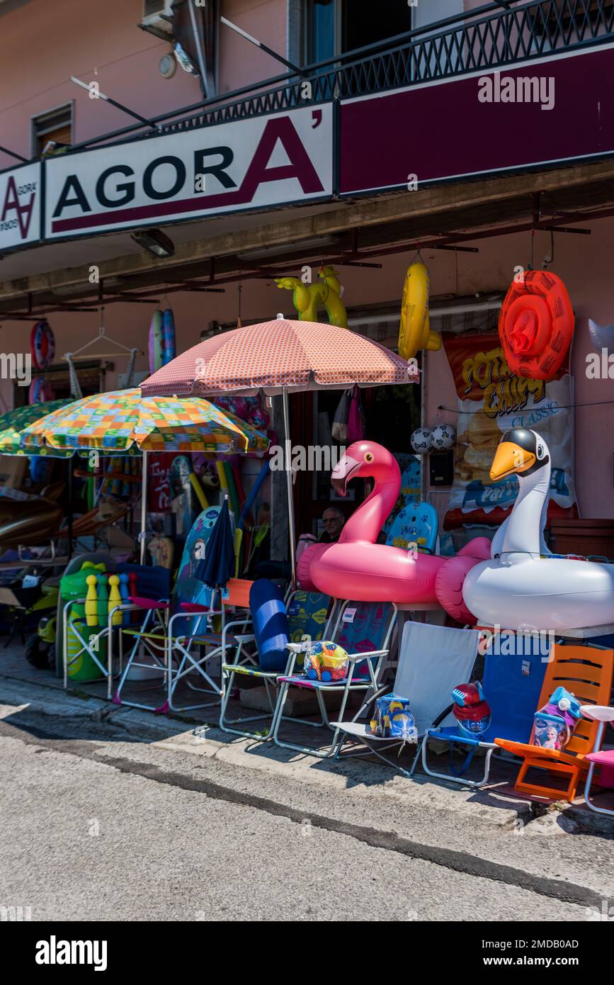 Paestum, Capaccio, Salerno, Italy - August 1, 2018: Beach umbrellas, chairs and floats in front of shop Stock Photo