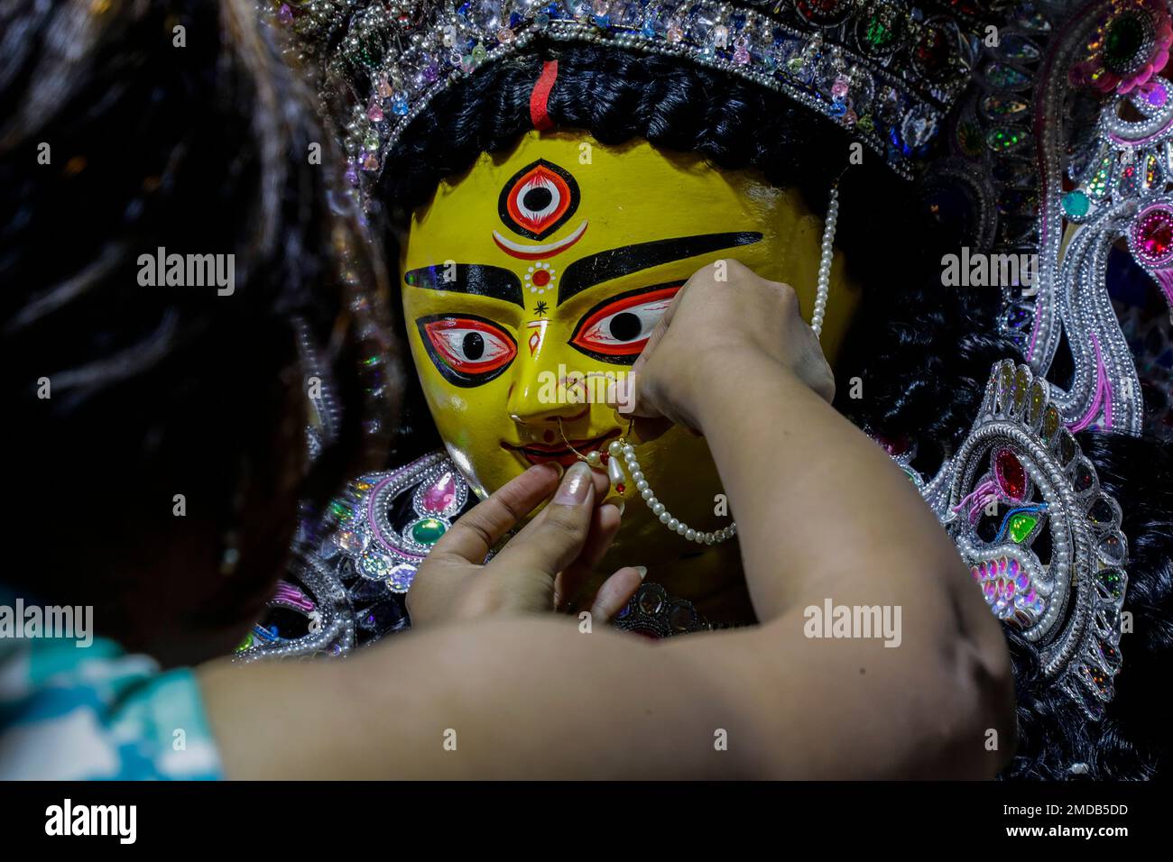 A girl puts nose ring to an idol of Hindu goddess Durga prior to worship in  Kolkata, India, Monday, Oct. 11, 2021. Durga Puja festival that starts on  Oct. 11 and ends
