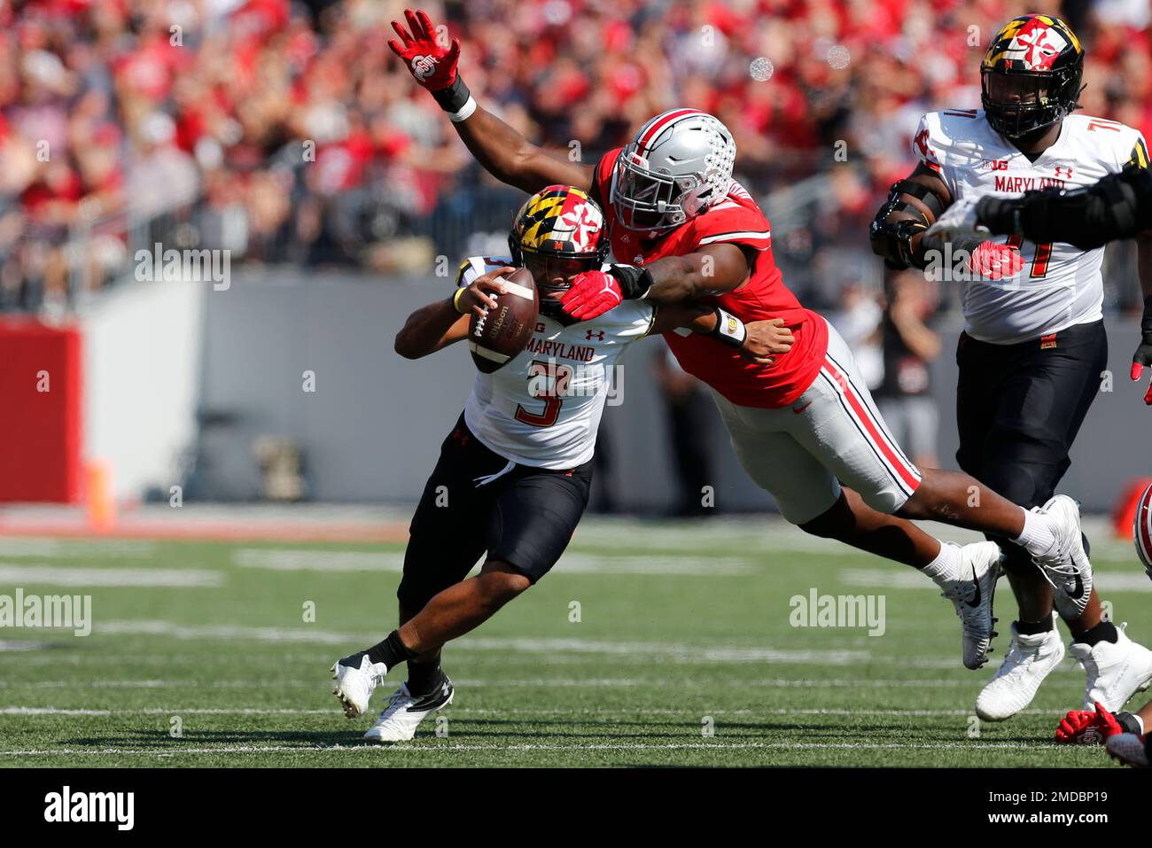 Ohio State defensive lineman Zach Harrison, right, tackles Maryland quarterback Taulia