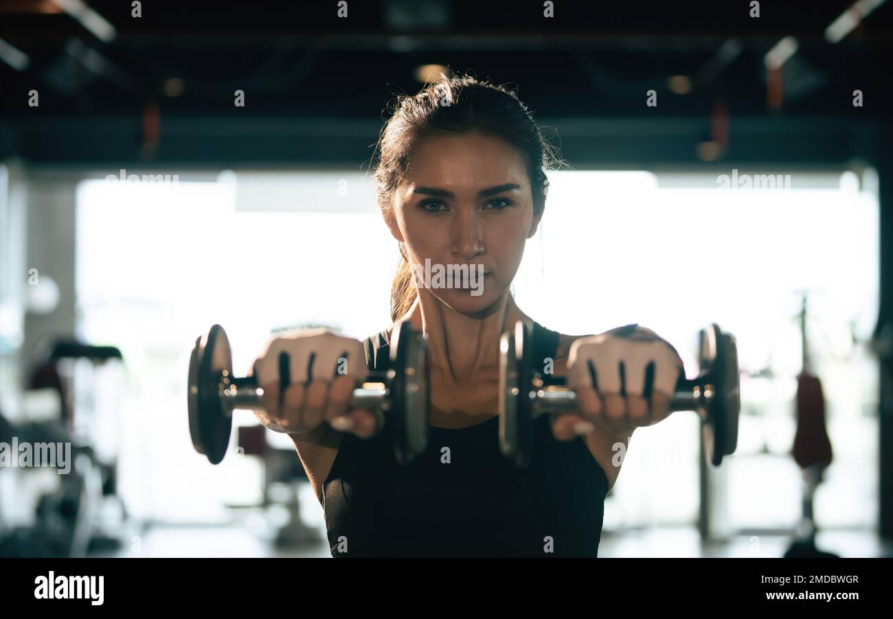 Young woman lifting dumbbells in the gym. Stock Photo