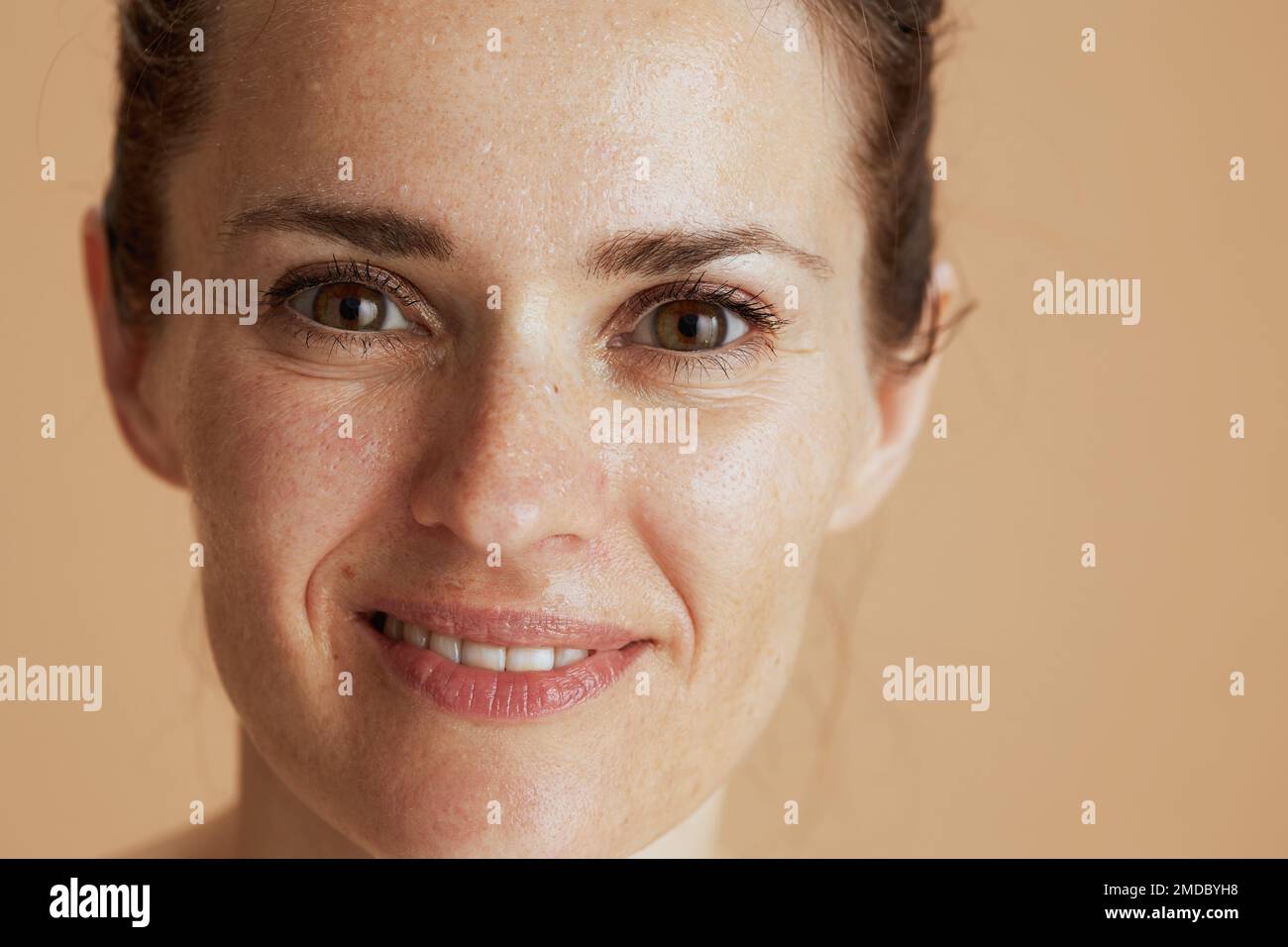 smiling modern woman with wet face washing isolated on beige. Stock Photo