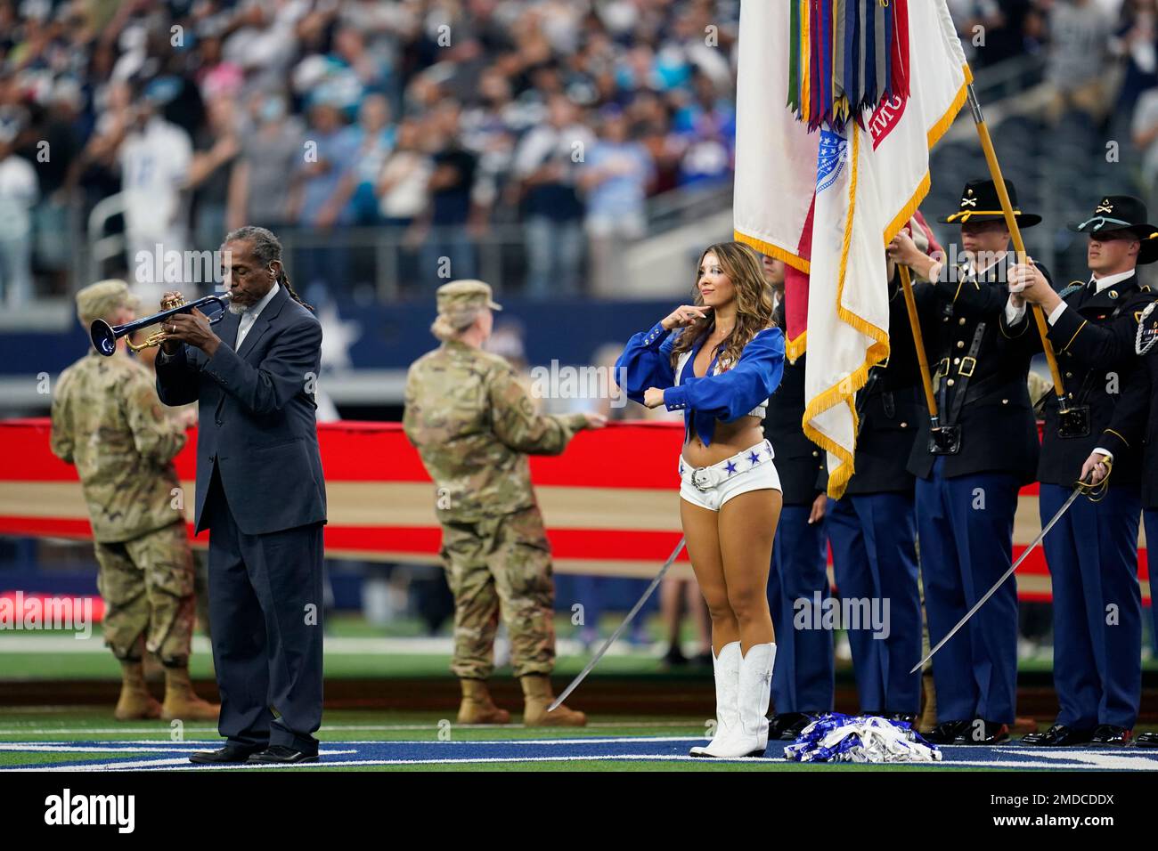 A Dallas Cowboys cheerleader performs sign language while trumpeter Freddie Jones play the ...