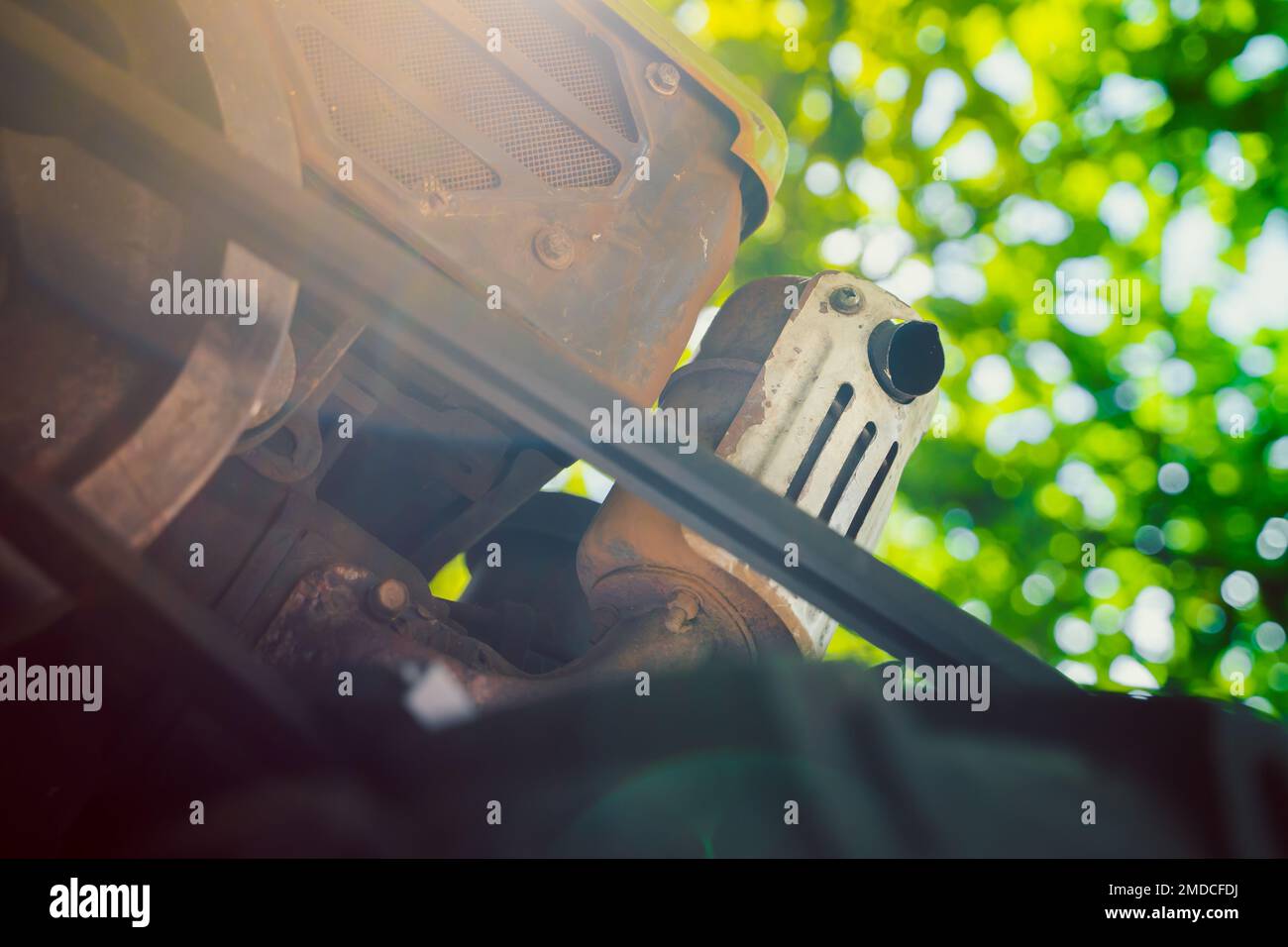 The muffler of the exhaust pipe of a walk-behind tractor on a blurred