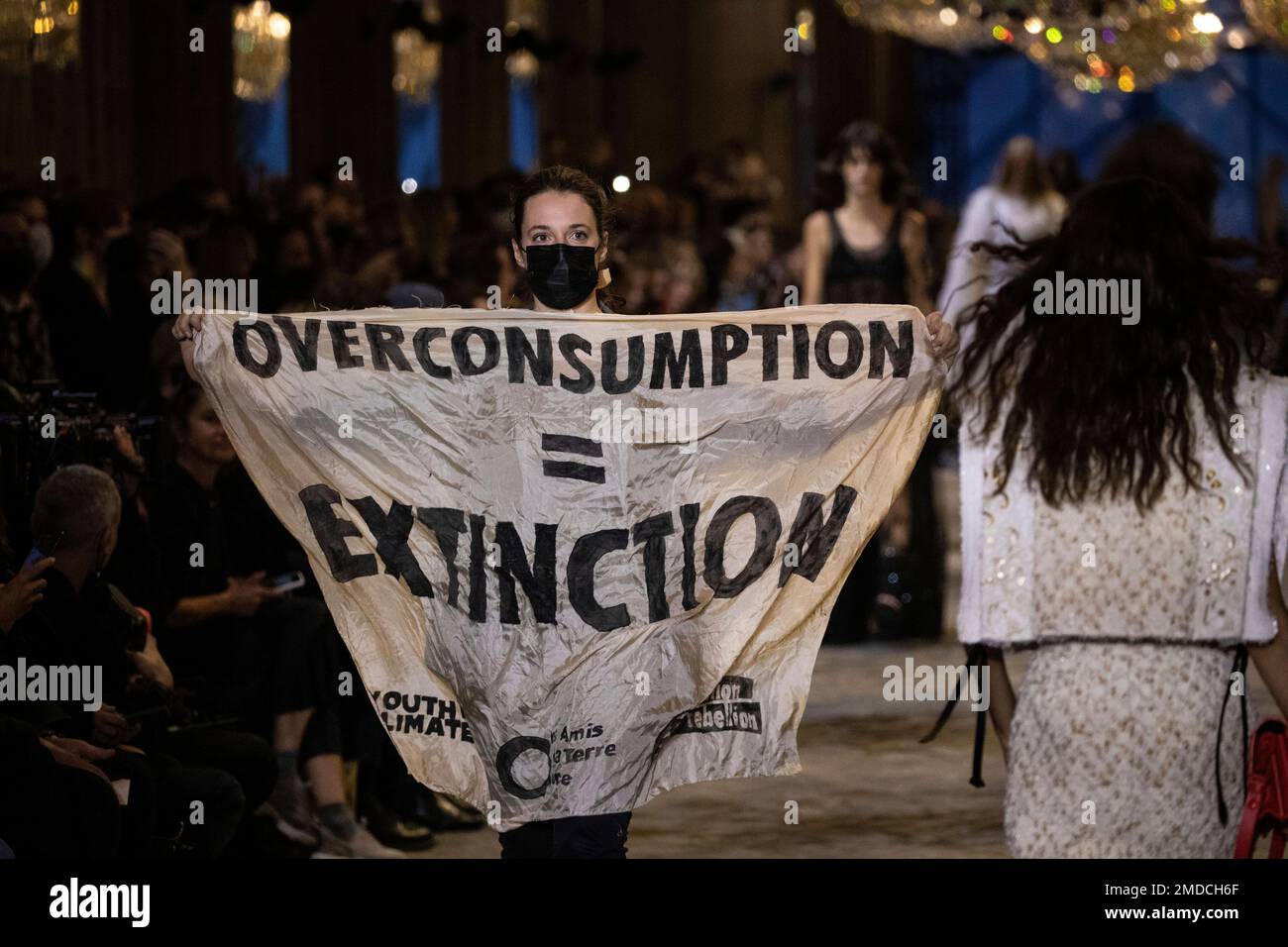 A protestor holds a banner on the runway during the Louis Vuitton