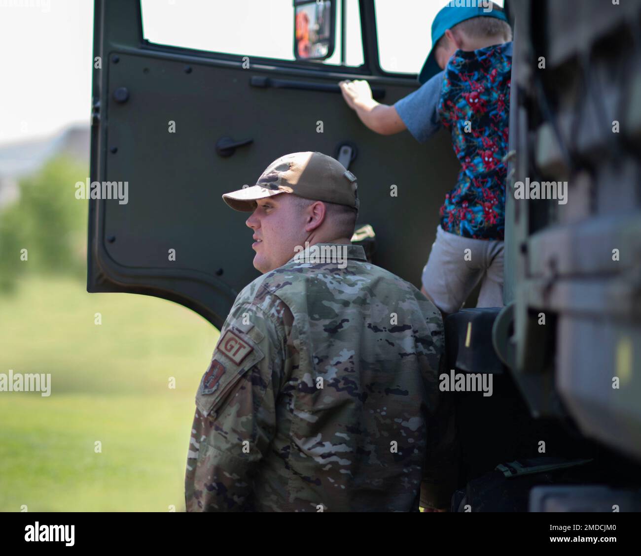 Staff Sgt. Samuel McLane 141 LRS stands by while a child climbs down off of a Light Medium Tactical Vehicle in Liberty Lake, Wash. July 15, 2022.  The Airmen were out supporting the annual Touch-A-Truck event allowing both children and adults to check out heavy equipment from multiple agencies. Stock Photo