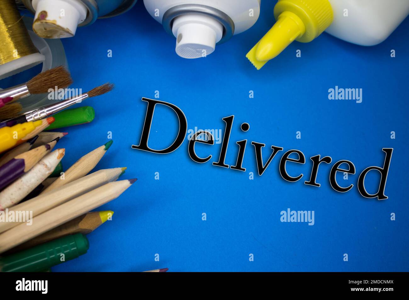 Overhead shot of school supplies with Delivered text. Brushes, pencils