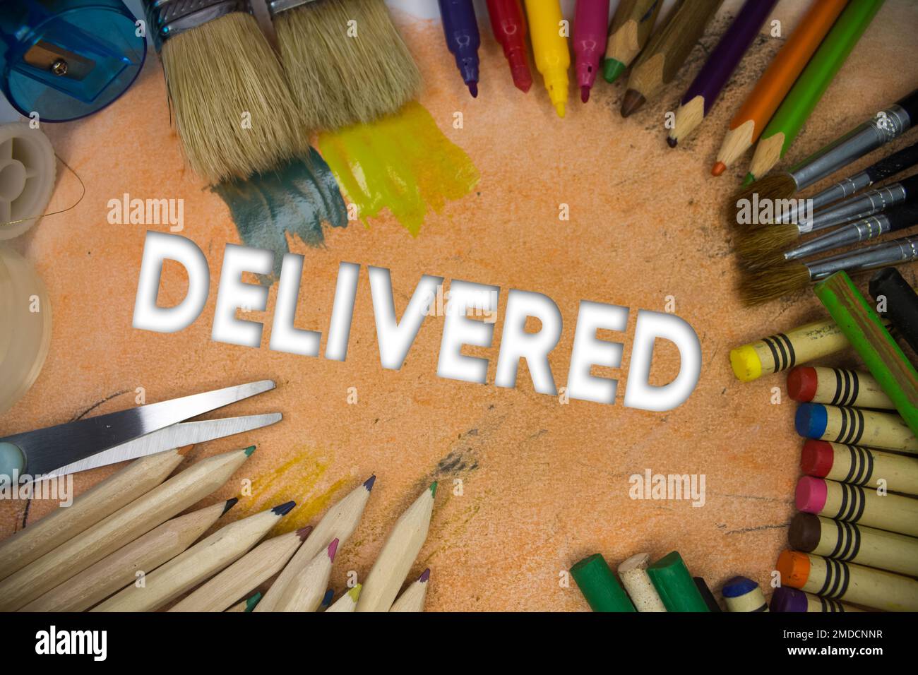 Overhead shot of school supplies with Delivered text. Brushes, pencils