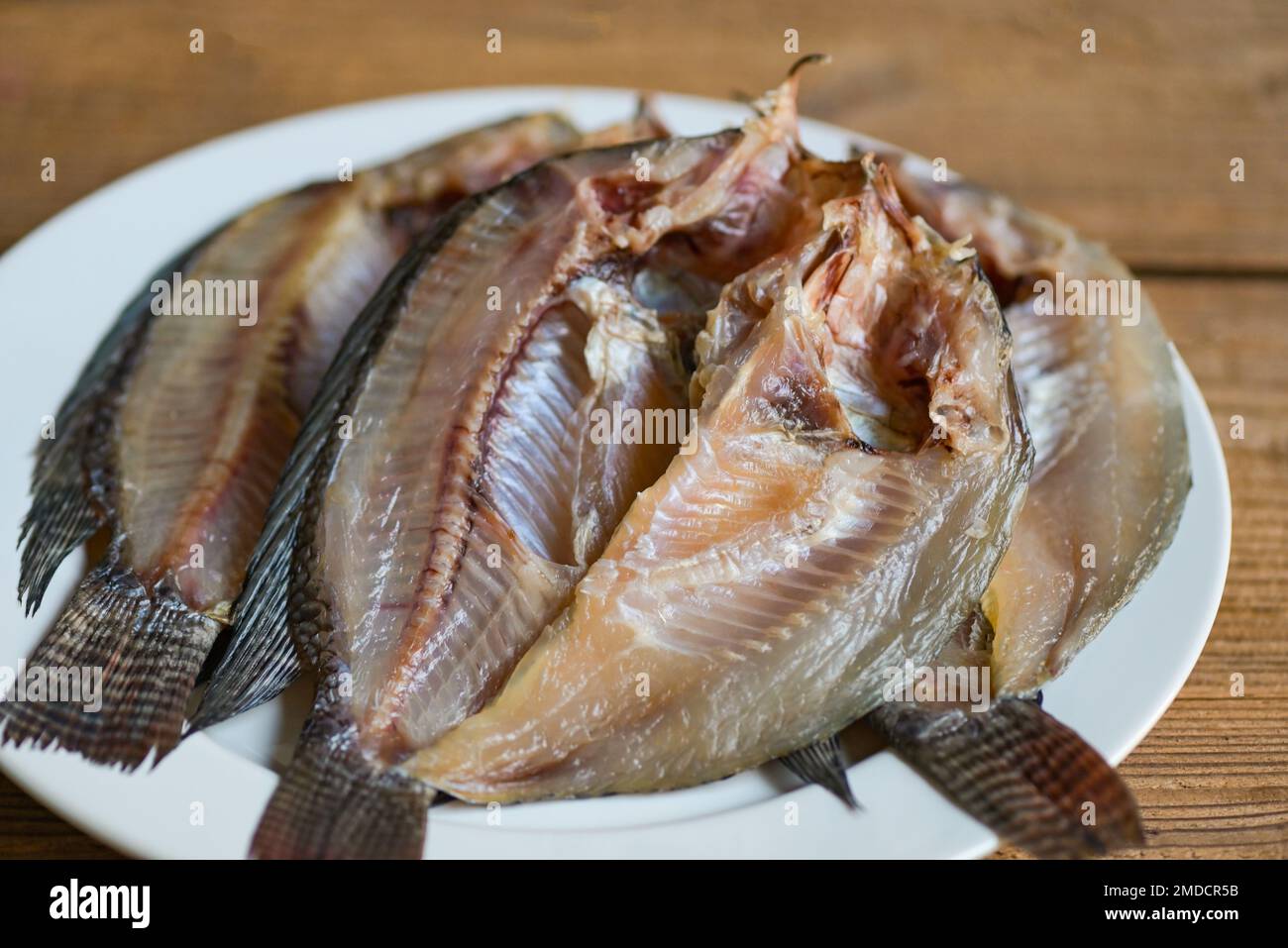 dried fish on white plate, tilapia fish for cooking food on wooden