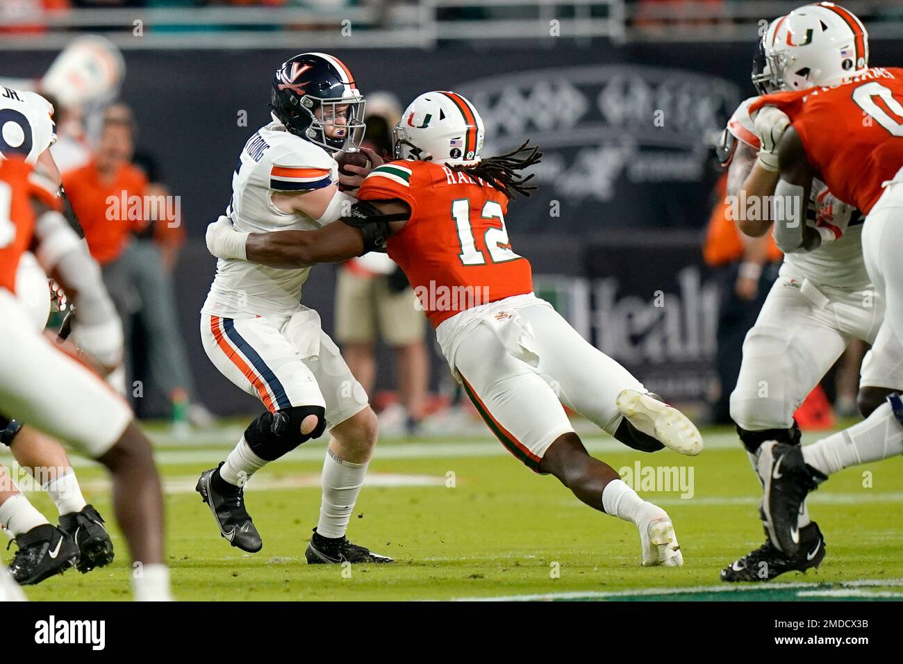 Virginia quarterback Brennan Armstrong, left is sacked by Miami