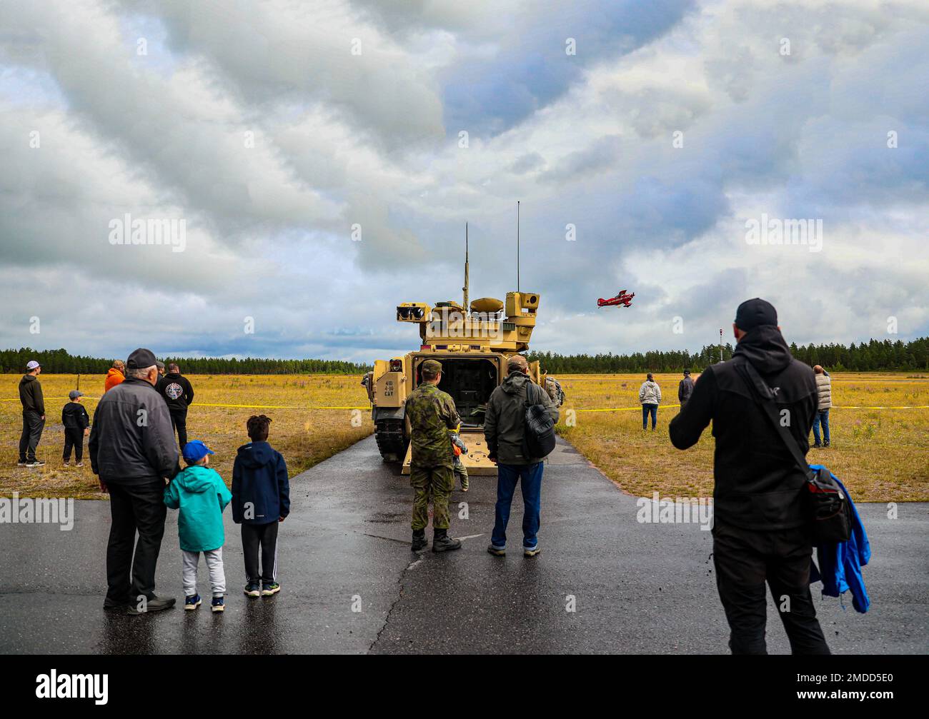 Finnish citizens watch a plane fly as a U.S. Army M2 Bradley Fighting Vehicle assigned to the 4th Squadron, 10th Cavalry Regiment, 3rd Armored Brigade Combat Team, 4th Infantry Division, is displayed during the Oripää Airshow at Säkylä, Finland, July 16, 2022. The 3rd Armored Brigade Combat Team, 4th Infantry Division, and the Pori Brigade of the Finnish army began summer training in Finland to strengthen relations and help build interoperability between the two nations. Stock Photo