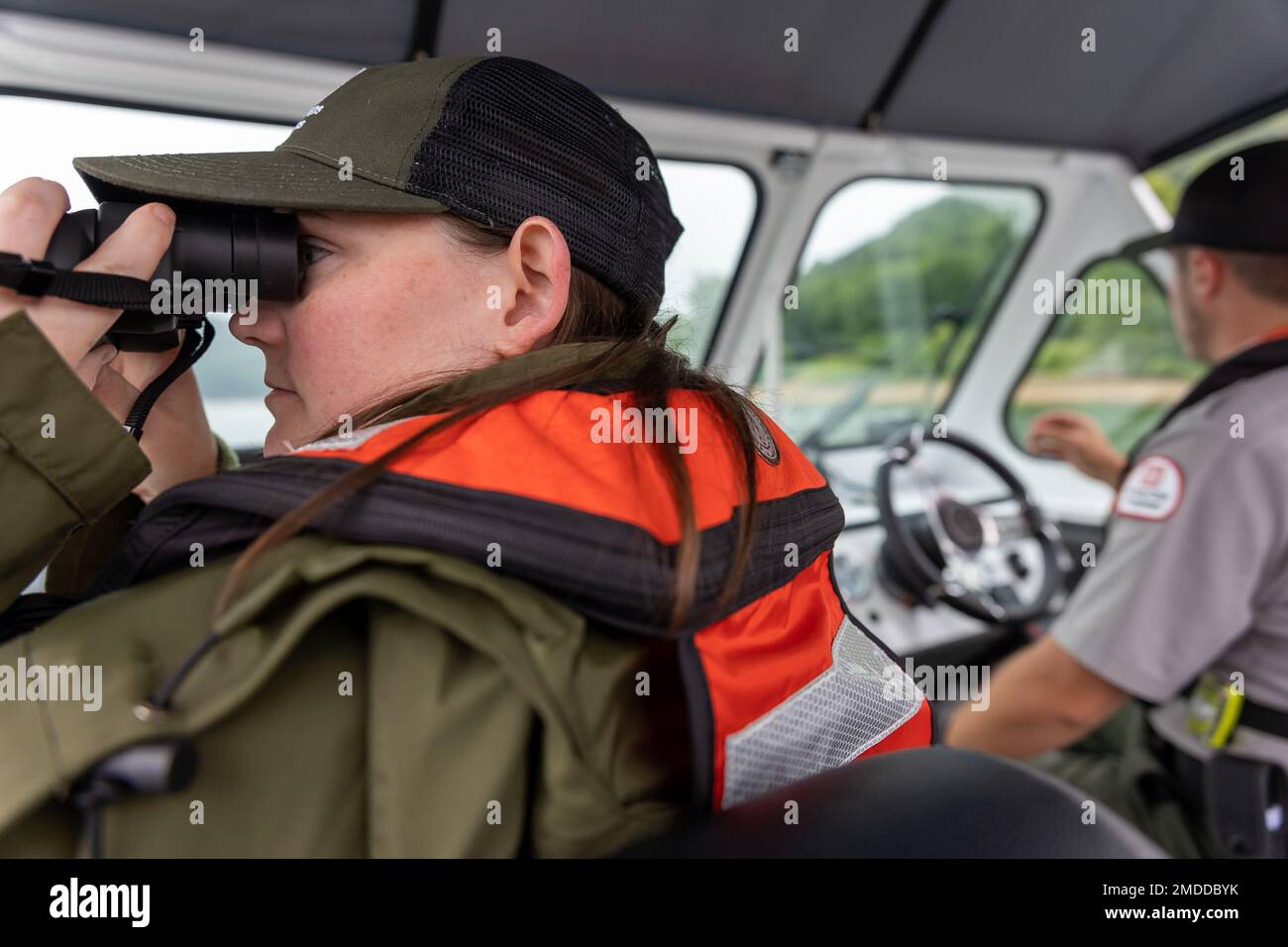 Sam Phillips, a summer park ranger with U.S. Army Corps of Engineers Pittsburgh District, uses binoculars to take a closer look at boaters to ensure they’re wearing life jackets on Youghiogheny River Lake in Confluence, Pennsylvania, July 15, 2022. “We’re trying to keep everybody safe and happy on the water,” said Phillips. Stock Photo