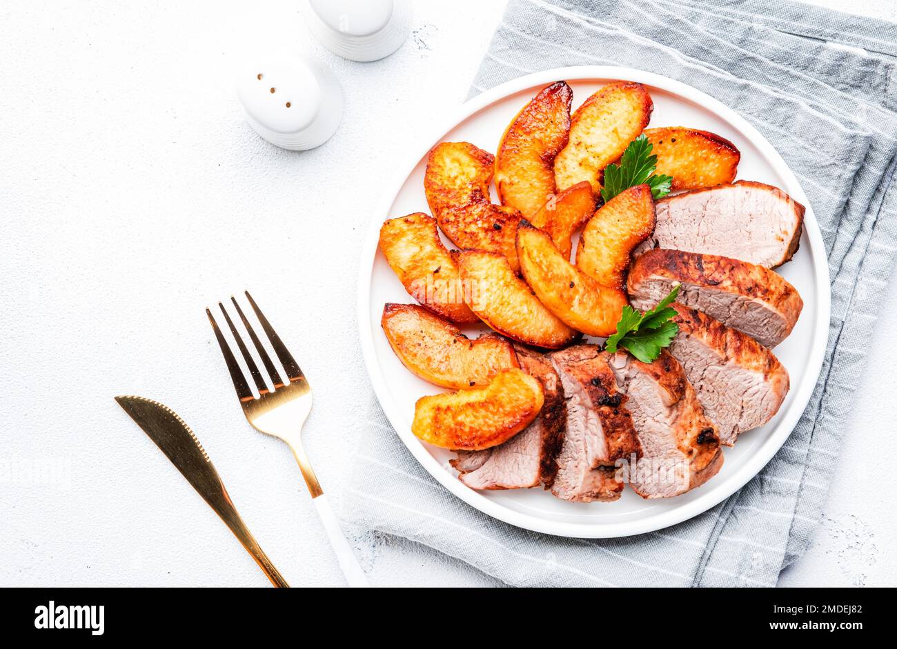 Baked pork tenderloin with quince or apple slices served on plate