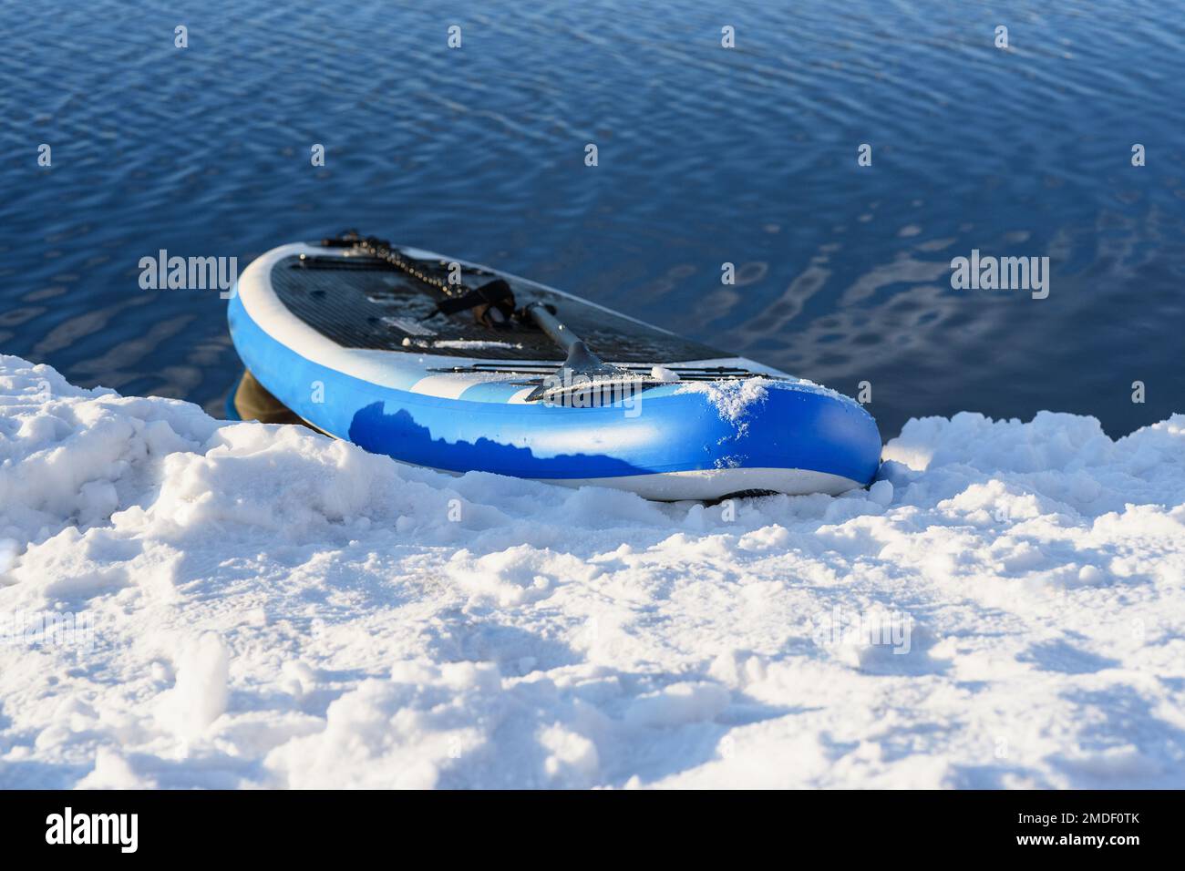 SUP board in snow and water in winter. Winter season and active leisure concept Stock Photo