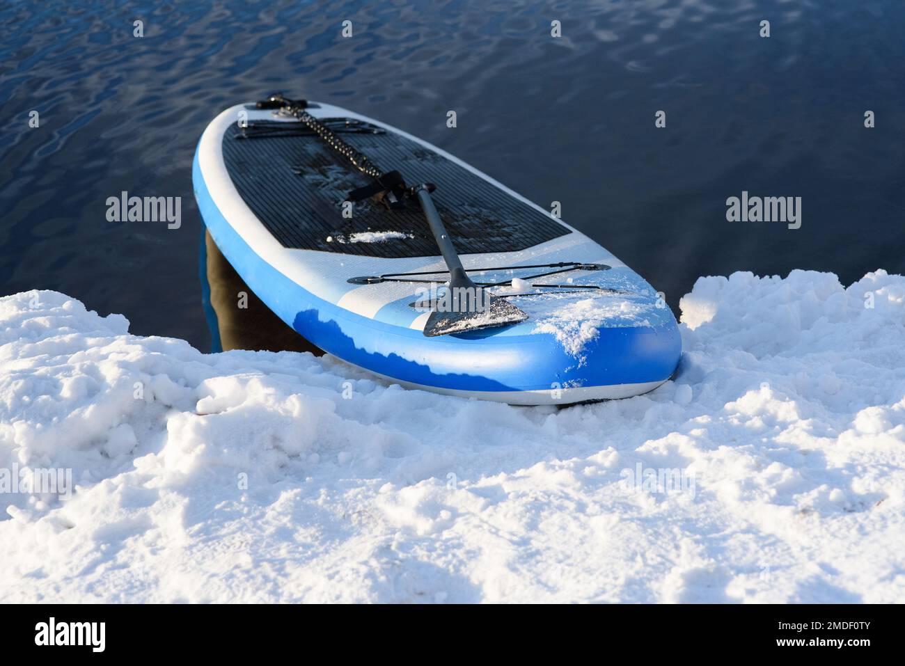 SUP board in snow and water in winter. Winter season and active leisure concept Stock Photo