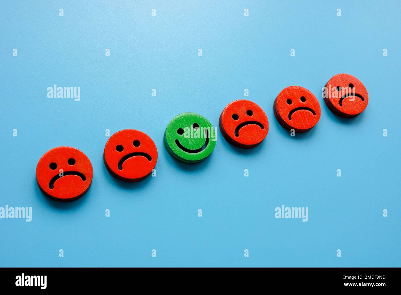 Line of sad emoticons and one happy as symbol of positivity. Stock Photo