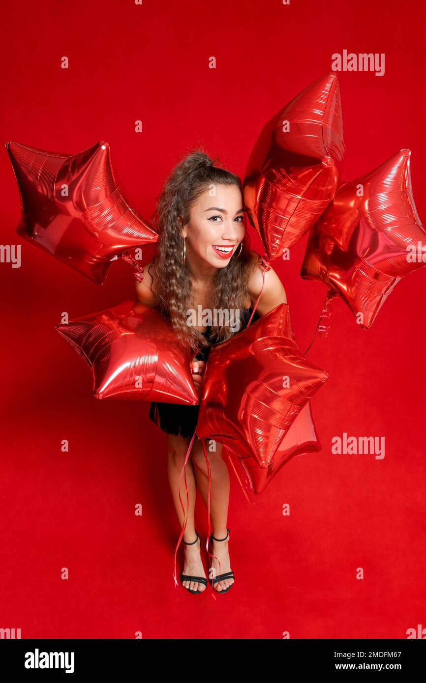 Candid content portrait girl holding lot red balloons in form stars
