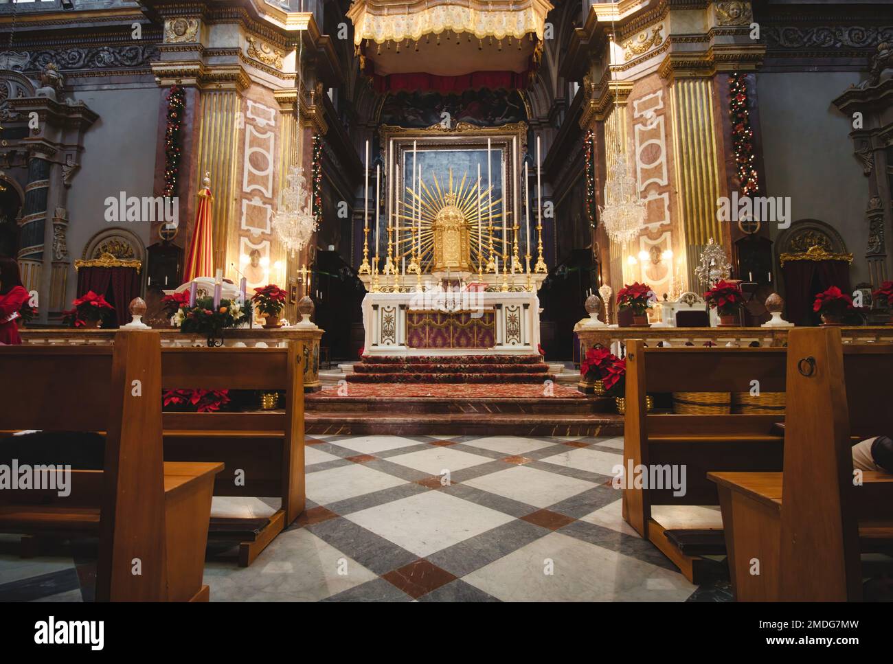 Front view of an altar in a large catholic church with wooden benches