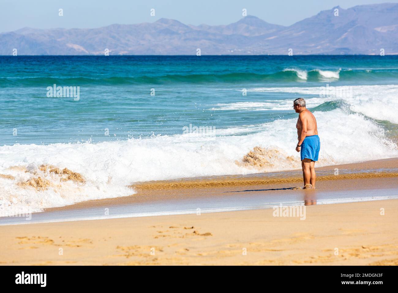Elderly man taking a foot bath in the sea on Cofete beach