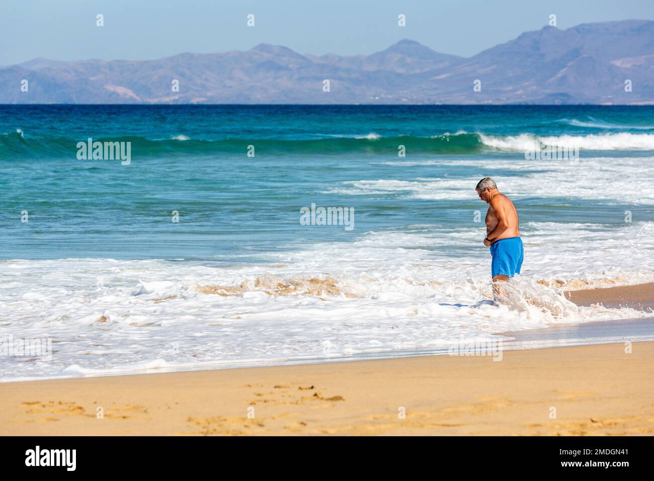 Elderly man taking a foot bath in the sea on Cofete beach