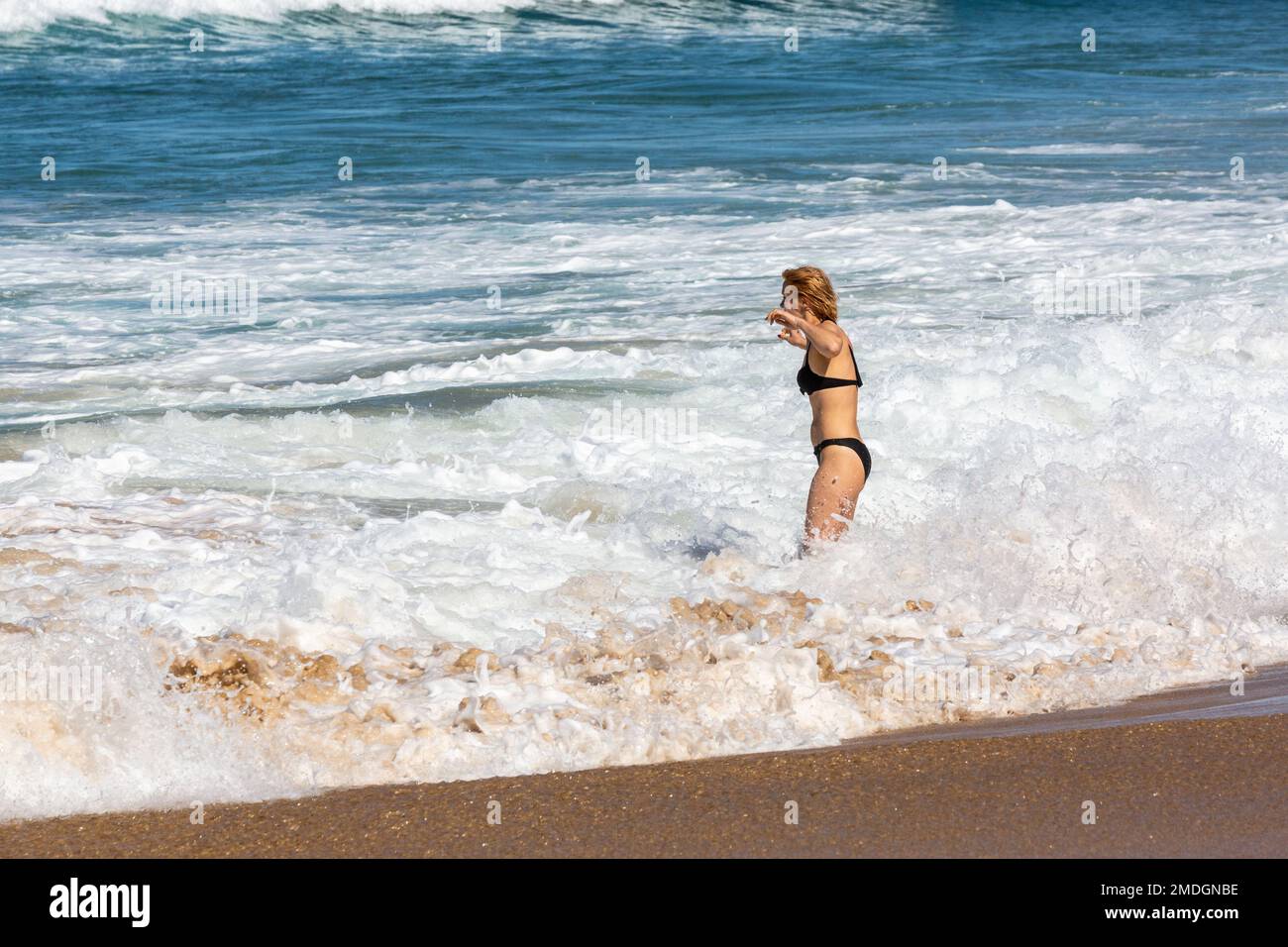 Young woman having a good time letting herself be caressed by the waves. Cofete Beach, Fuerteventura, Canary Islands Stock Photo