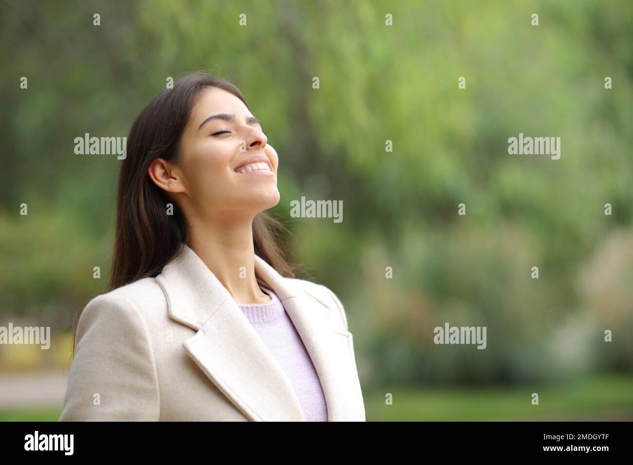 Happy woman in winter breaths fresh air in a park Stock Photo
