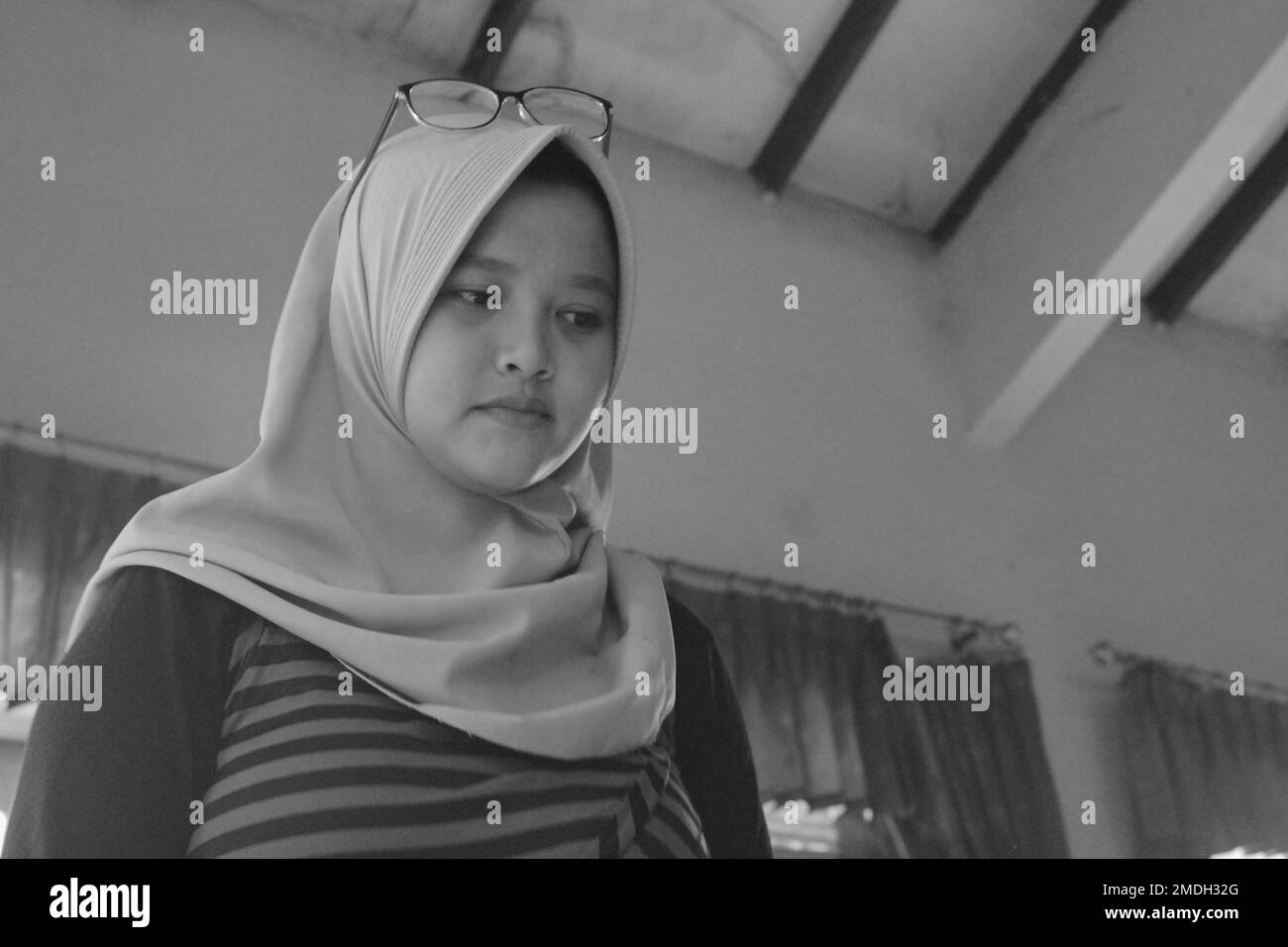 Jakarta, Indonesia - 02 24 2020: black and white photo of a woman wearing a hijab wearing glasses over her head during a college vacation Stock Photo
