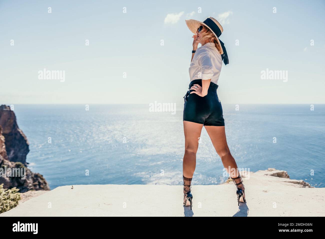 Woman sea hat. Business woman in yellow hat freelancer working over blue sea beach. Girl relieves stress from work. Freelance, digital nomad, travel Stock Photo