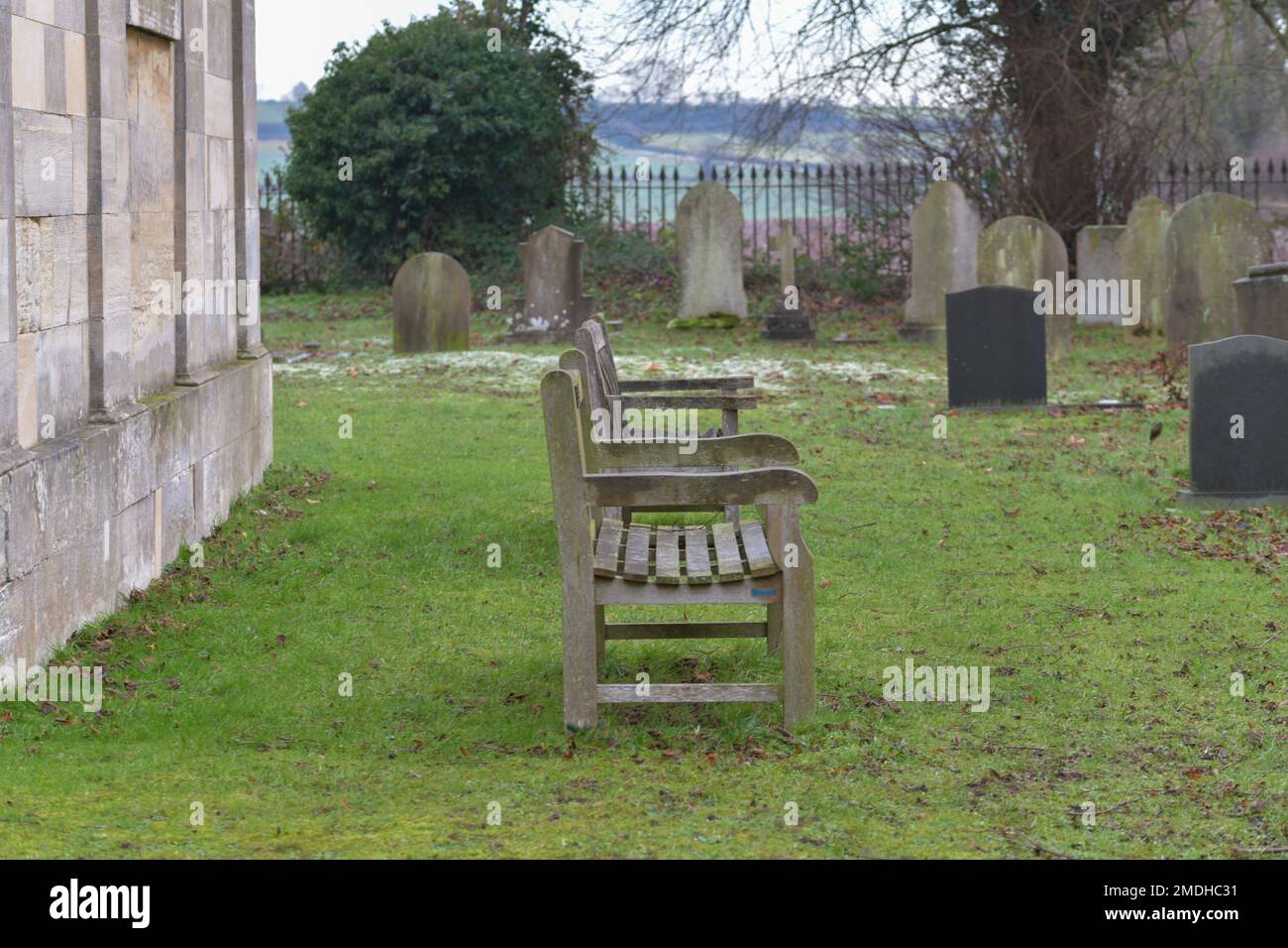 Two wooden benches sat empty in the grounds of a grave yard, solitary, time to think empty, remembrance Stock Photo