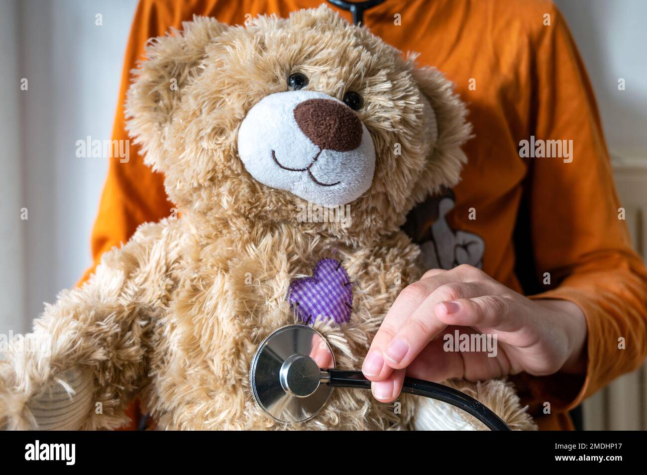 Child examines cuddly toy playfully with a stethoscope on the subject of pediatrician Stock Photo