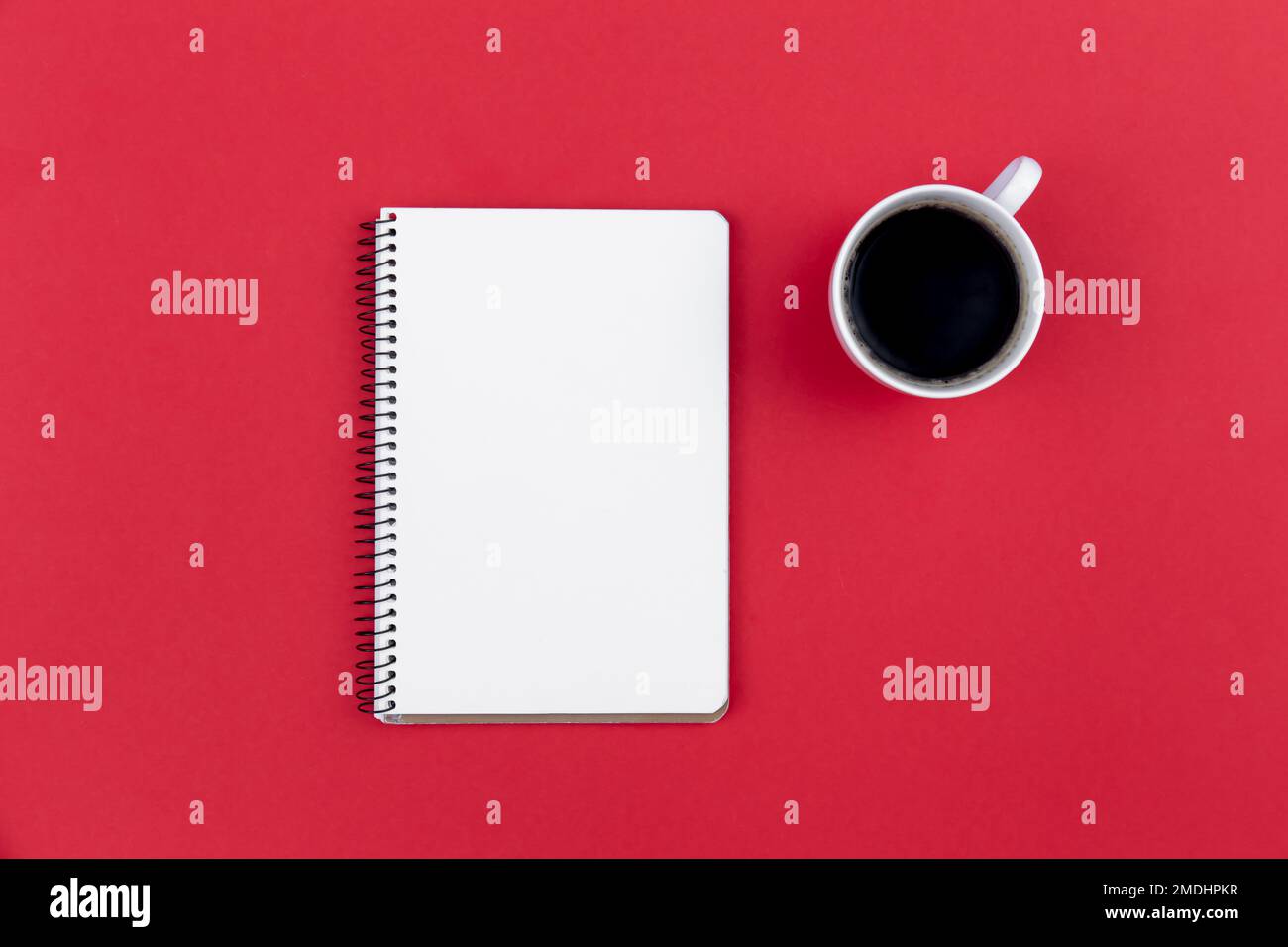Blank notepad and coffee cup on red background, flat lay. Stock Photo