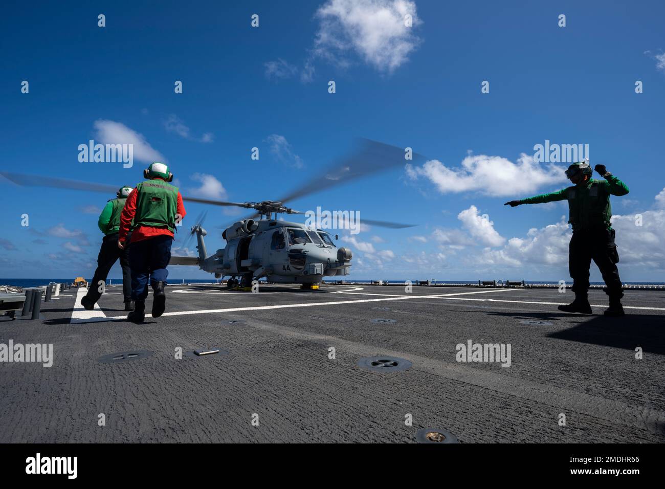 PACIFIC OCEAN (July 24, 2022) A U.S. Navy Sailor directs Navy and U.S. Coast Guard Sailors to a U.S. Navy MH-60R Seahawk helicopter during flight operations during Rim of the Pacific (RIMPAC) 2022. Twenty-six nations, 38 ships, three submarines, more than 170 aircraft and 25,000 personnel are participating in RIMPAC from June 29 to Aug. 4 in and around the Hawaiian Islands and Southern California. The worlds largest international maritime exercise, RIMPAC provides a unique training opportunity while fostering and sustaining cooperative relationships among participants critical to ensuring the Stock Photo