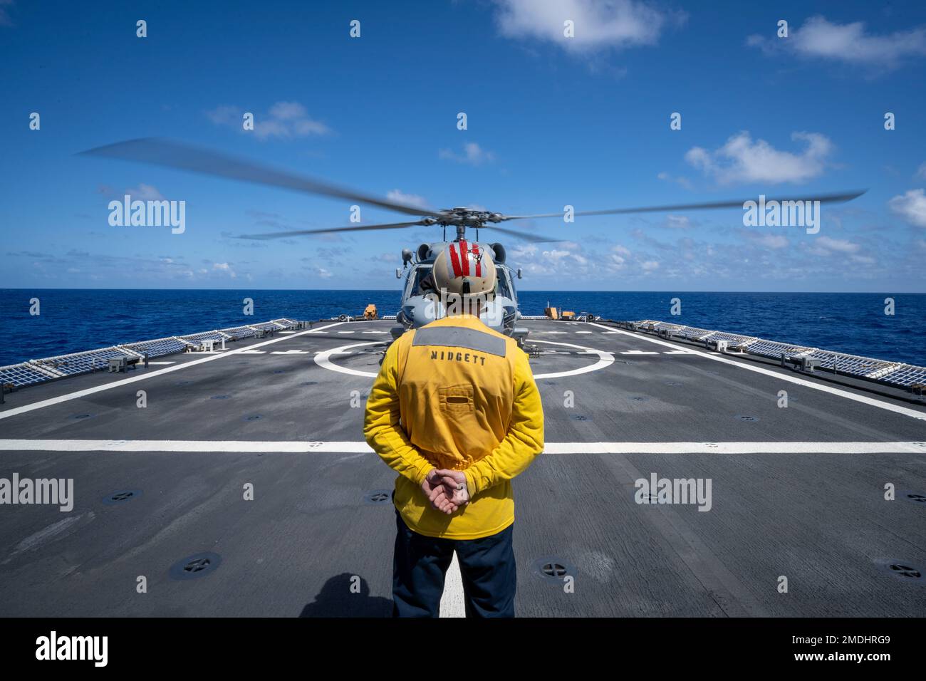 PACIFIC OCEAN (July 24, 2022) A U.S. Coast Guard Legend-class cutter USCGC Midgett (WMSL 757) Sailor stands by while a U.S. Navy MH-60R Seahawk helicopter spins up during flight operations during Rim of the Pacific (RIMPAC) 2022. Twenty-six nations, 38 ships, three submarines, more than 170 aircraft and 25,000 personnel are participating in RIMPAC from June 29 to Aug. 4 in and around the Hawaiian Islands and Southern California. The worlds largest international maritime exercise, RIMPAC provides a unique training opportunity while fostering and sustaining cooperative relationships among partic Stock Photo