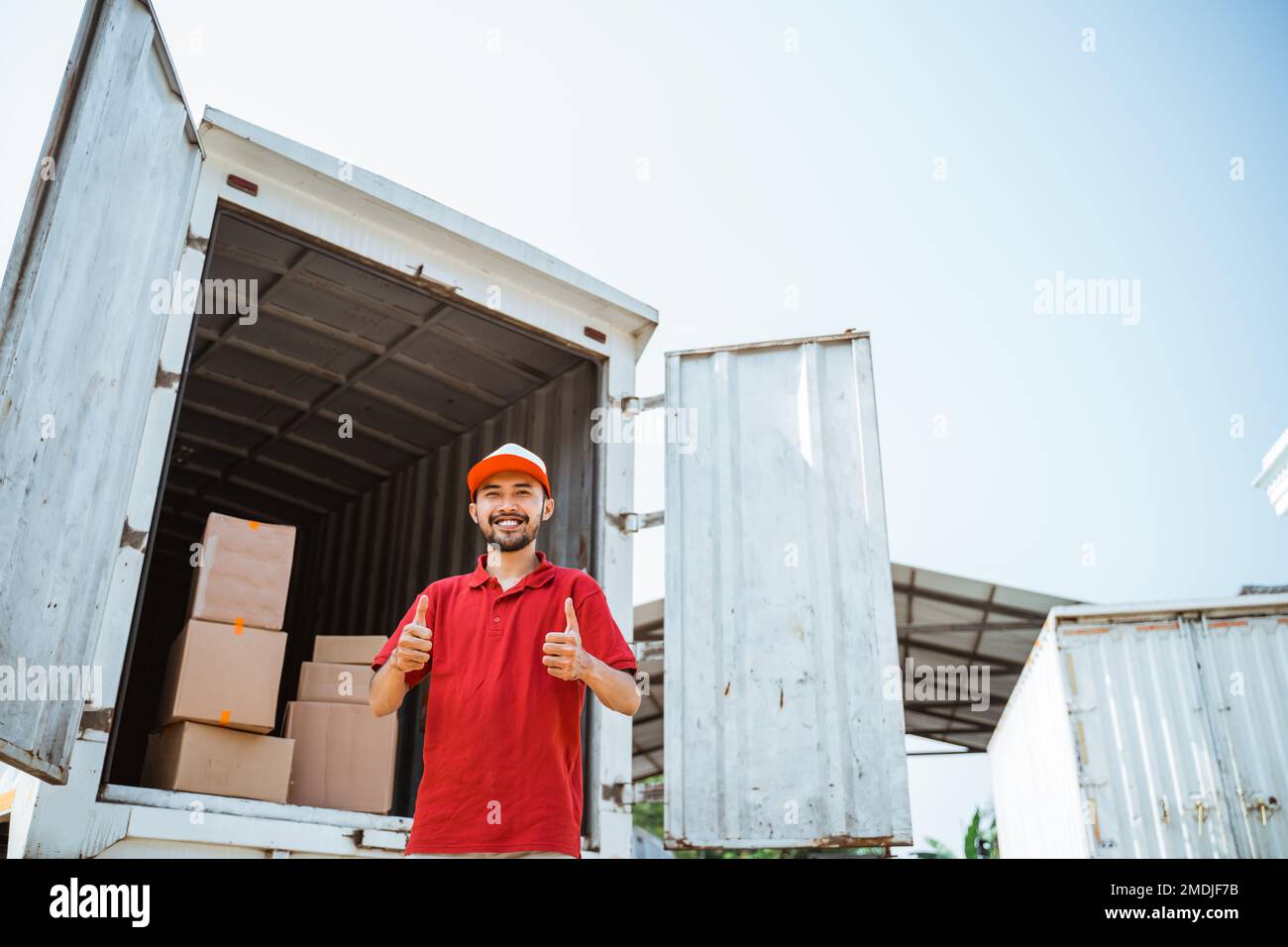 warehouse workers in red smiling with thumbs up Stock Photo
