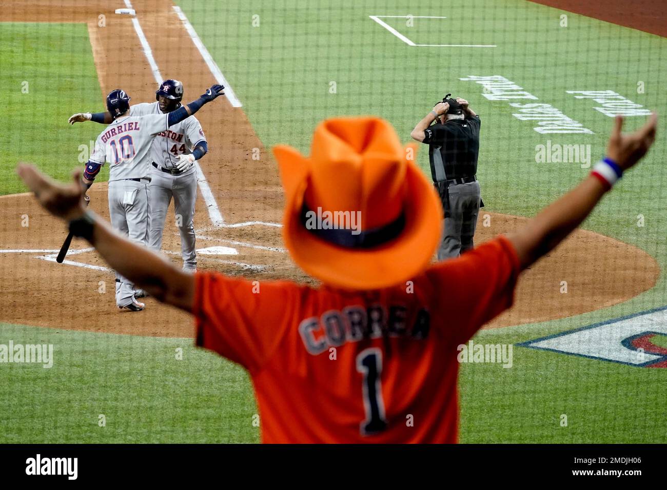 Houston Astros fan Mark McKee, of Beaumont, Texas, celebrates as he watches  the Astros' Yuli Gurriel (10) congratulate Yordan Alvarez (44) on his  two-run home run as umpire Larry Vanover stands by