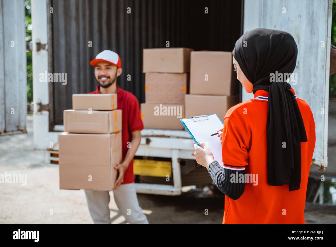 female worker with notes checking the package by delivery man Stock Photo