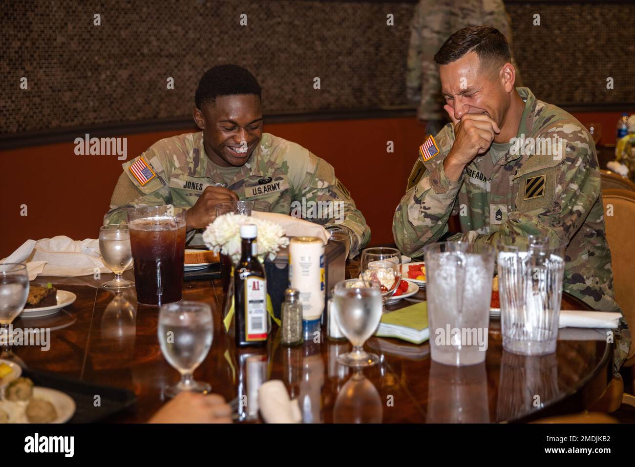 U.S. Army Spc. Darquiarean Jones and Sgt. 1st Class Mk-Ada-Quet Genereaux, both assigned to 3rd Infantry Division, laugh together before they eat a meal together to kick off the Best Squad Competition at Fort Stewart, Georgia, July 25, 2022. Squads from throughout XVIII Airborne Corps are competing in Best Squad Competition, which will test them in a number of areas including marksmanship, land navigation, small-unit tactics and endurance. Stock Photo