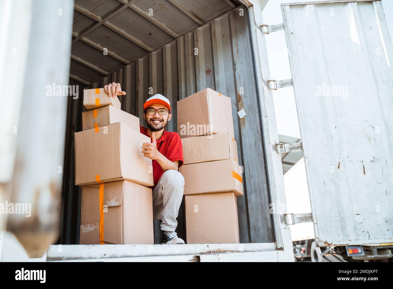 delivery man with thumbs up working unloading boxes from containers Stock Photo