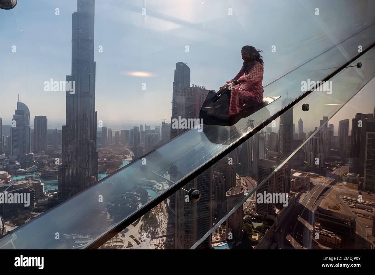 Dubai, UAE , United Arab Emirates. November 28th, 2022. tourists roll down a glass slide on the Sky View skyscraper. Dangerous scary attraction. Stock Photo