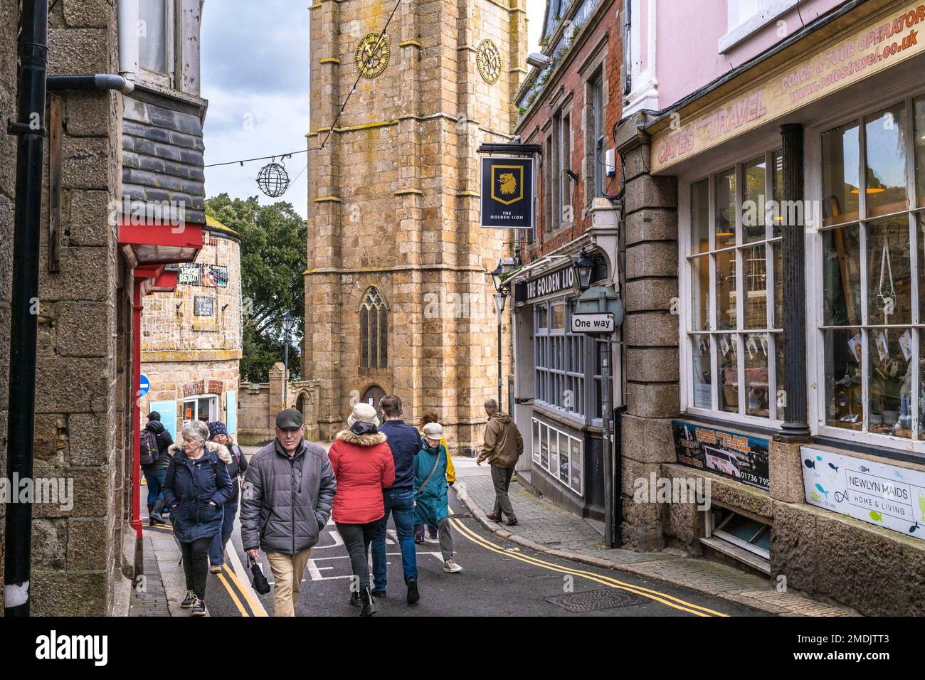 Visitors walking along St Andrews Street with St Eia Church in the background in the historic coastal town of St Ives in Cornwall in England in the UK Stock Photo