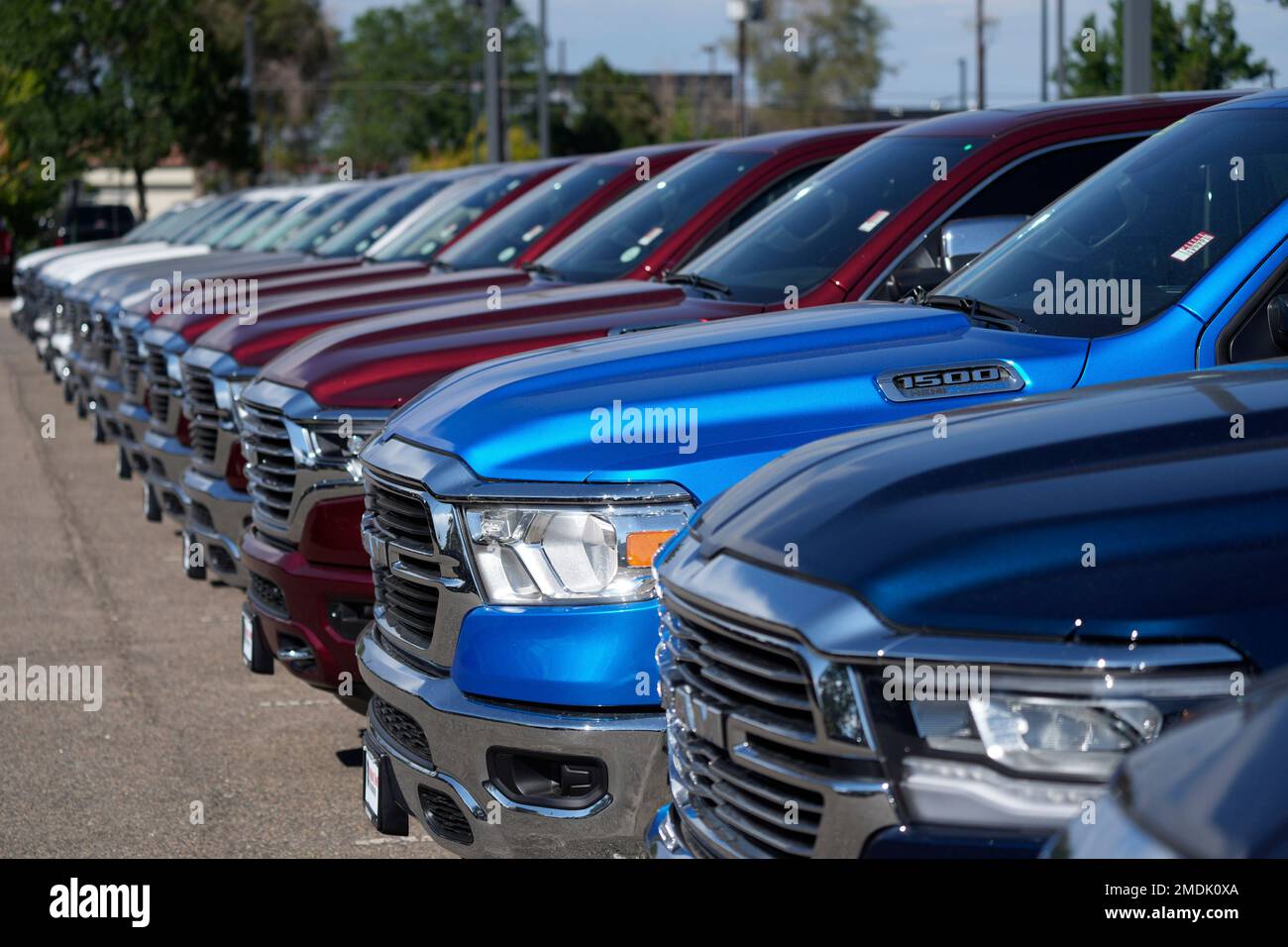 A lone line of unsold 2021 pickup trucks in an empty storage lot at a