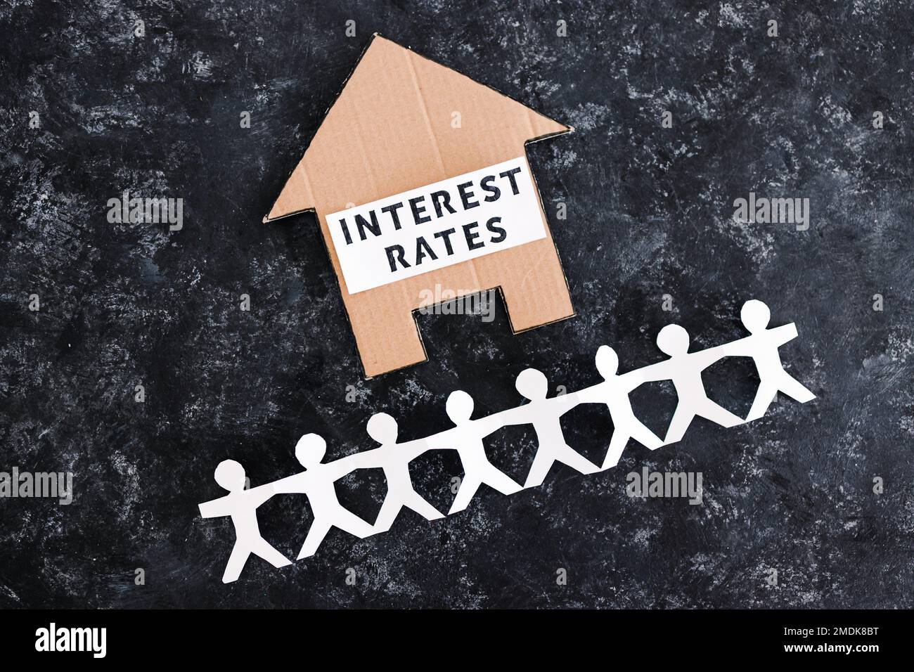 interest rates and home loan affordability conceptual image, text on cardboard house with paper people chain underneath symbol of potential clients Stock Photo