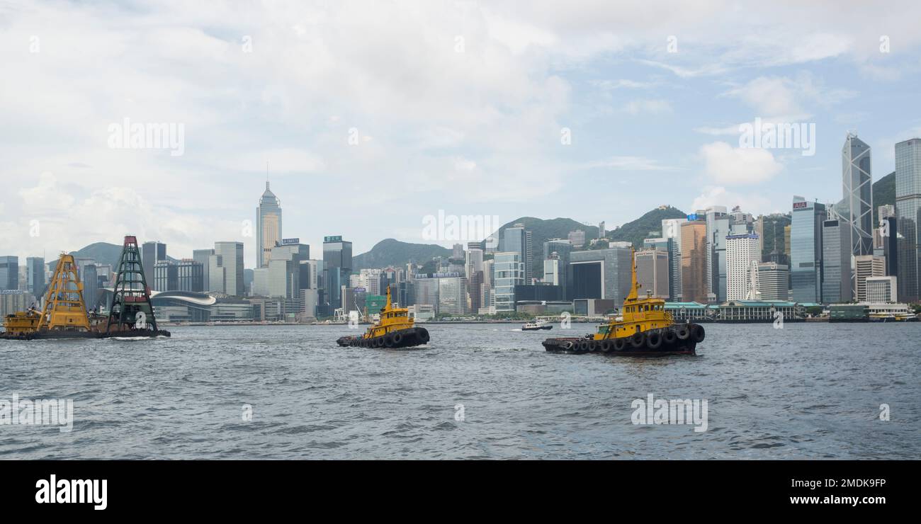 Two tugs towing pile barge, Hong Kong harbour Stock Photo