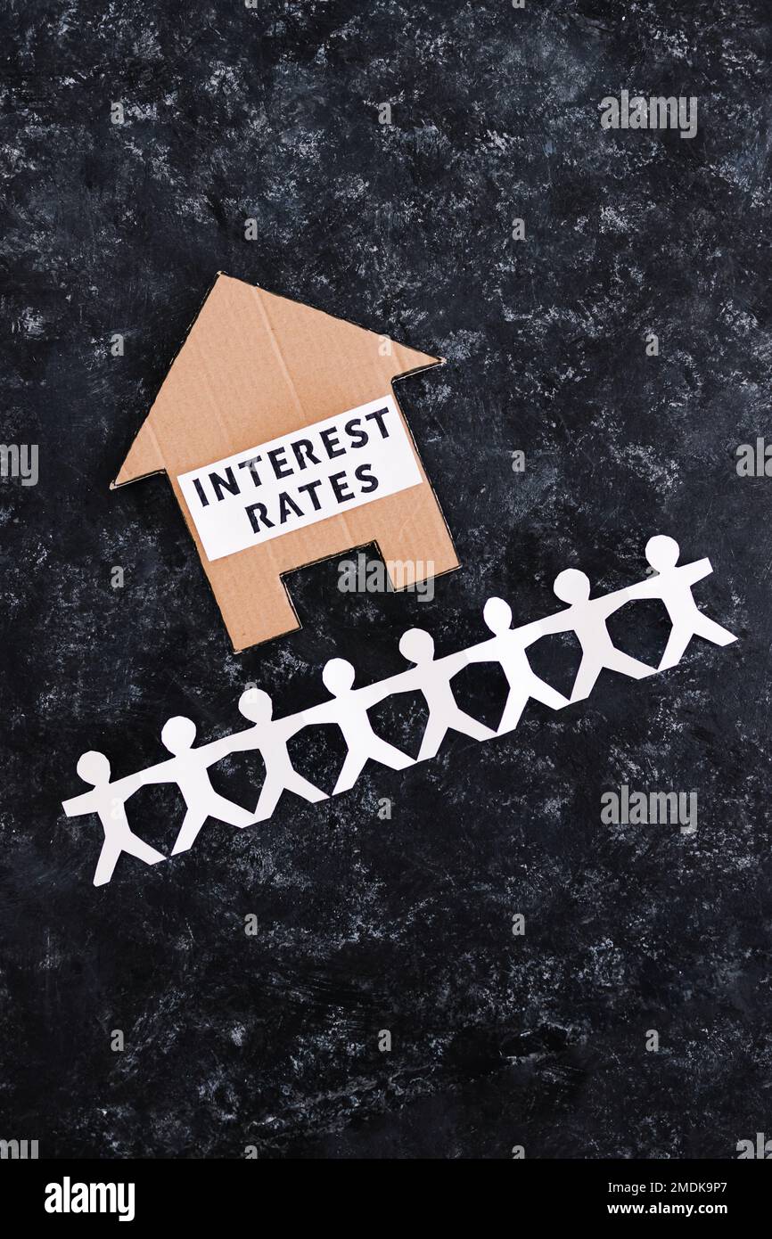 interest rates and home loan affordability conceptual image, text on cardboard house with paper people chain underneath symbol of potential clients Stock Photo