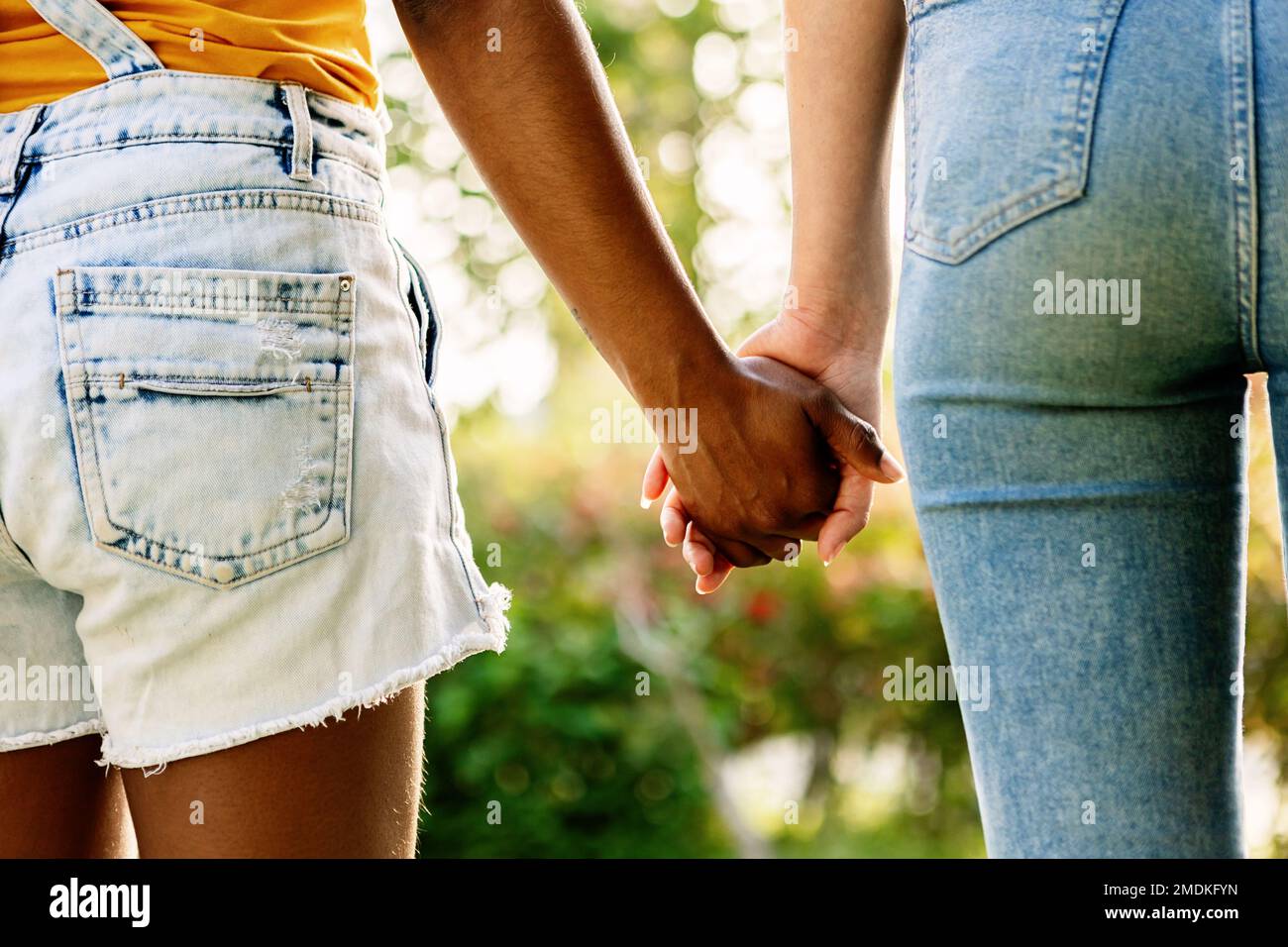 Multiracial young female couple holding hands outdoors Stock Photo