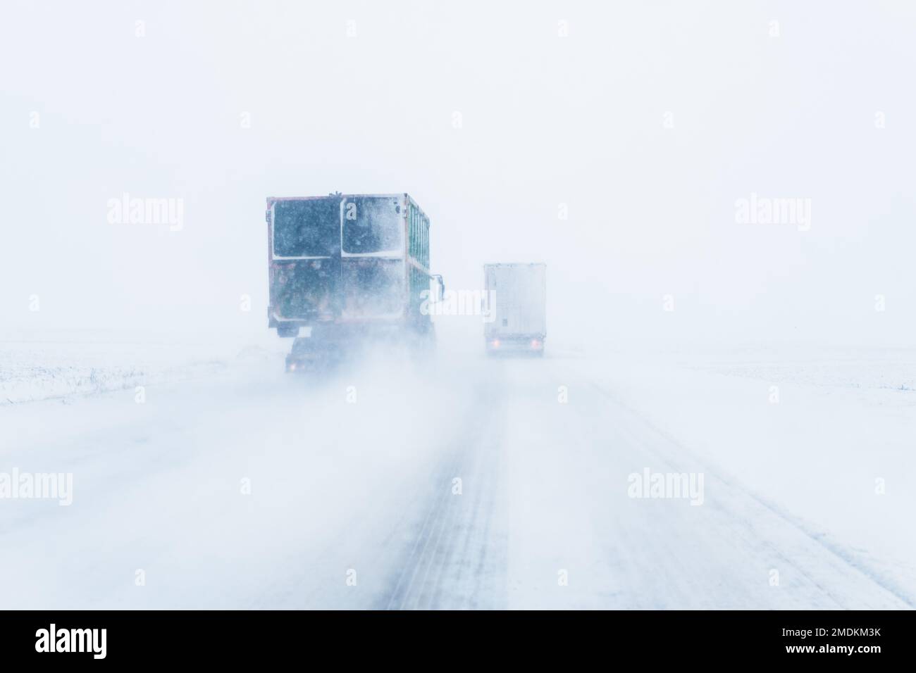 Freight transportation truck on the road in snow storm blizzard, bad weather conditions for transportation event, selective focus Stock Photo