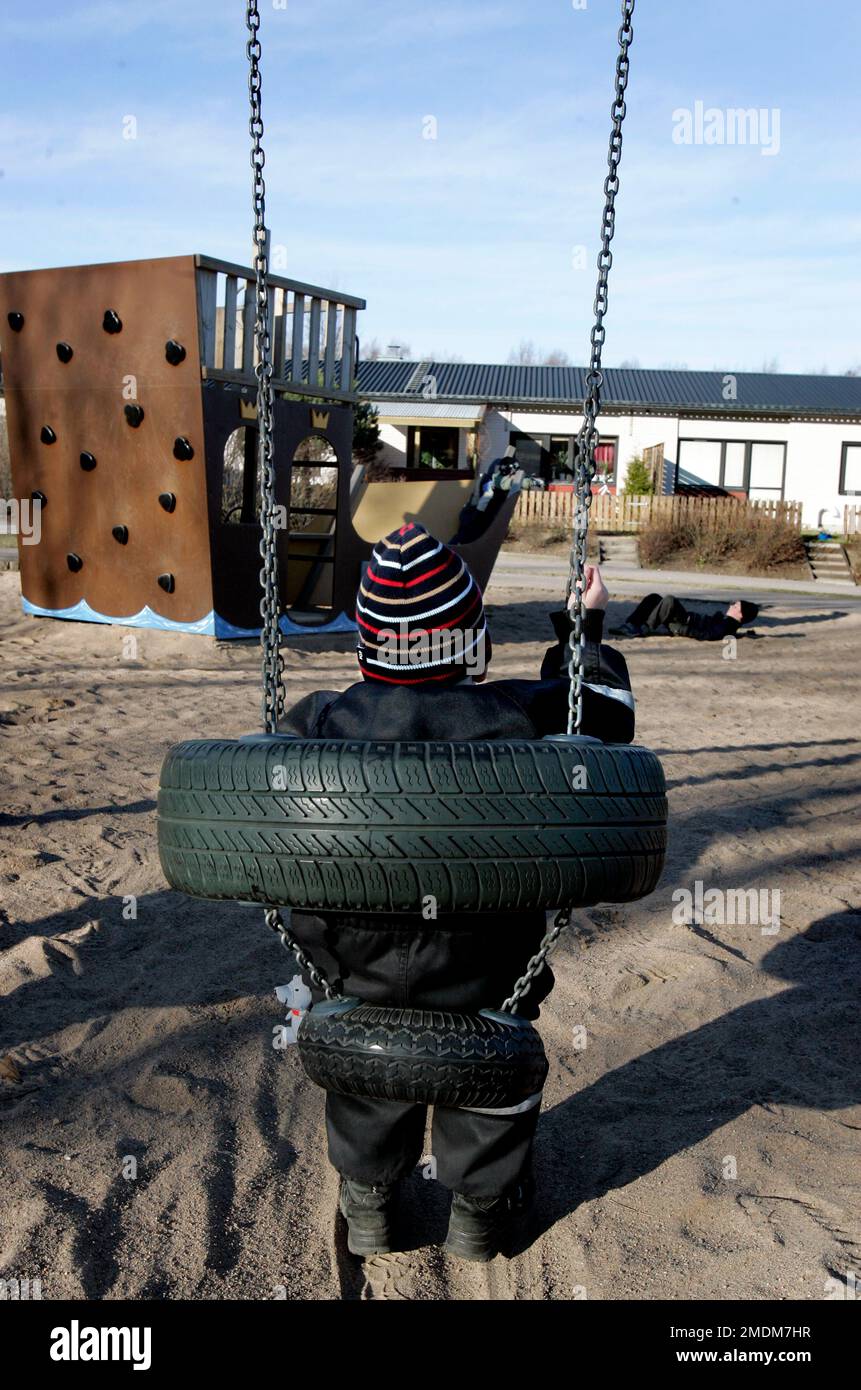 A playground for children, children in a swing in a residential area. Stock Photo