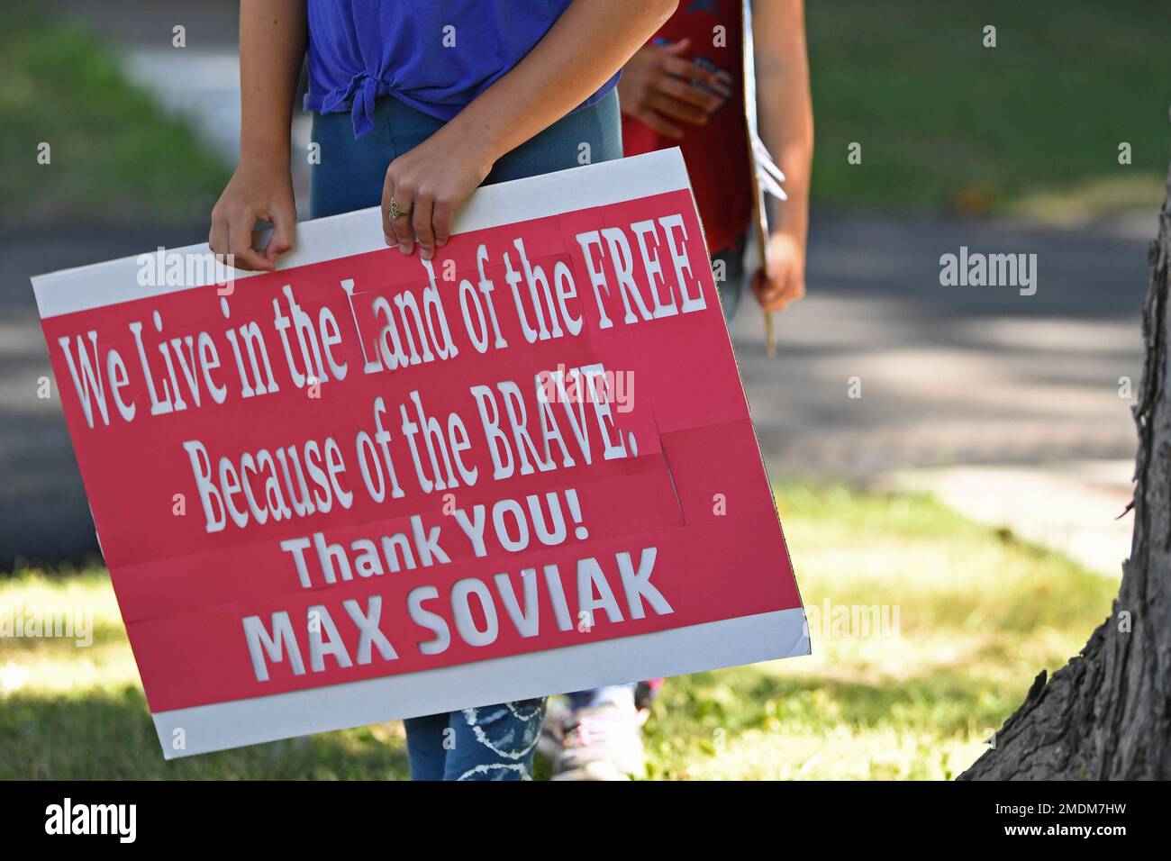 Tymber Mason holds a sign to show support for Navy Corpsman Maxton Soviak near the procession