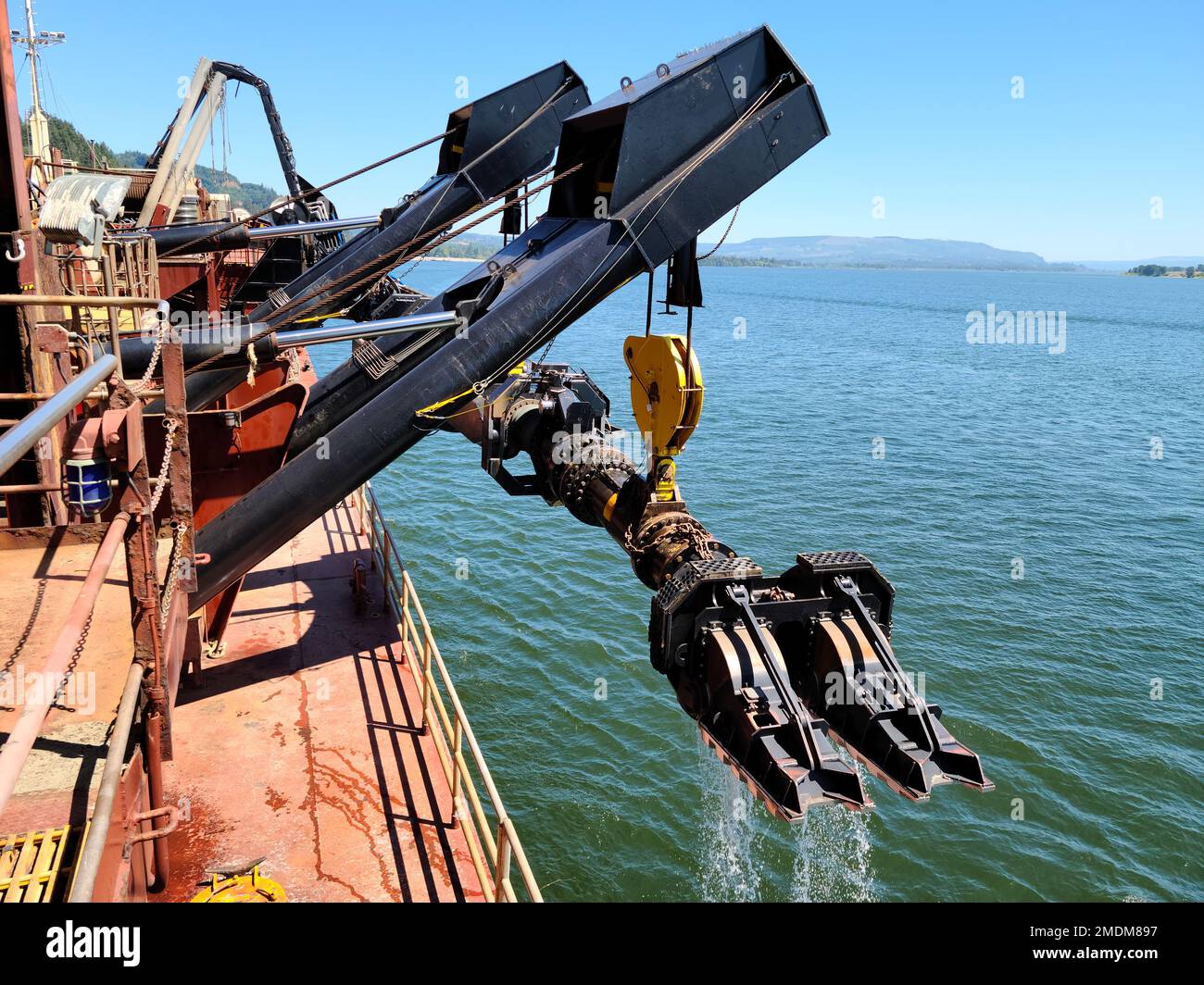 The Essayons, one of two hopper dredges owned and operated by the Portland District, U.S. Army Corps of Engineers, performs emergency dredging on the lower Columbia River near Longview, Washington, July 25. The dredge, operated by a merchant marine crew, helps maintain the entrance bars, rivers and harbors on the coasts of California, Oregon, Hawaii, Alaska and, in emergencies, the Mississippi River. In this photo, the dredge’s drag arm—which acts like a vacuum cleaner head to suck up sediment from the bottom of rivers and harbors—is being raised out of the water. Stock Photo