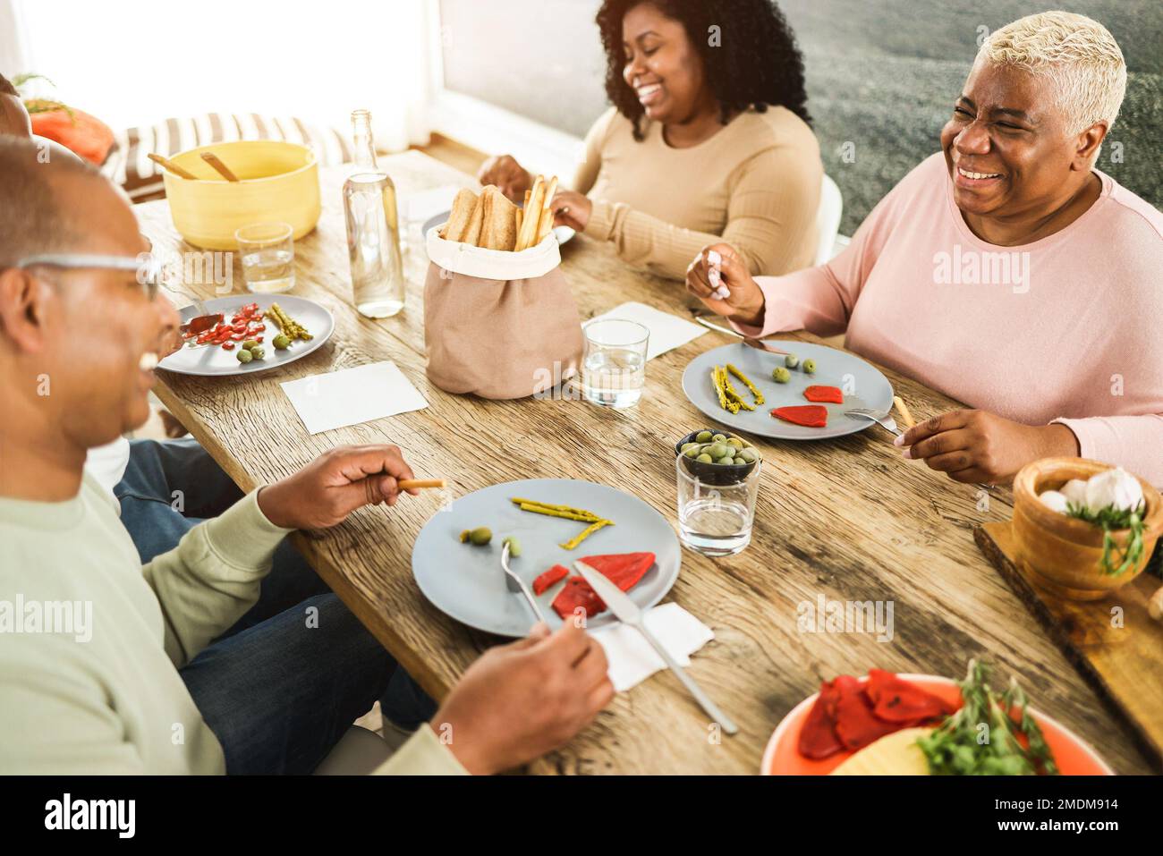 Happy african family eating lunch together at home - Soft focus on mother right hand Stock Photo